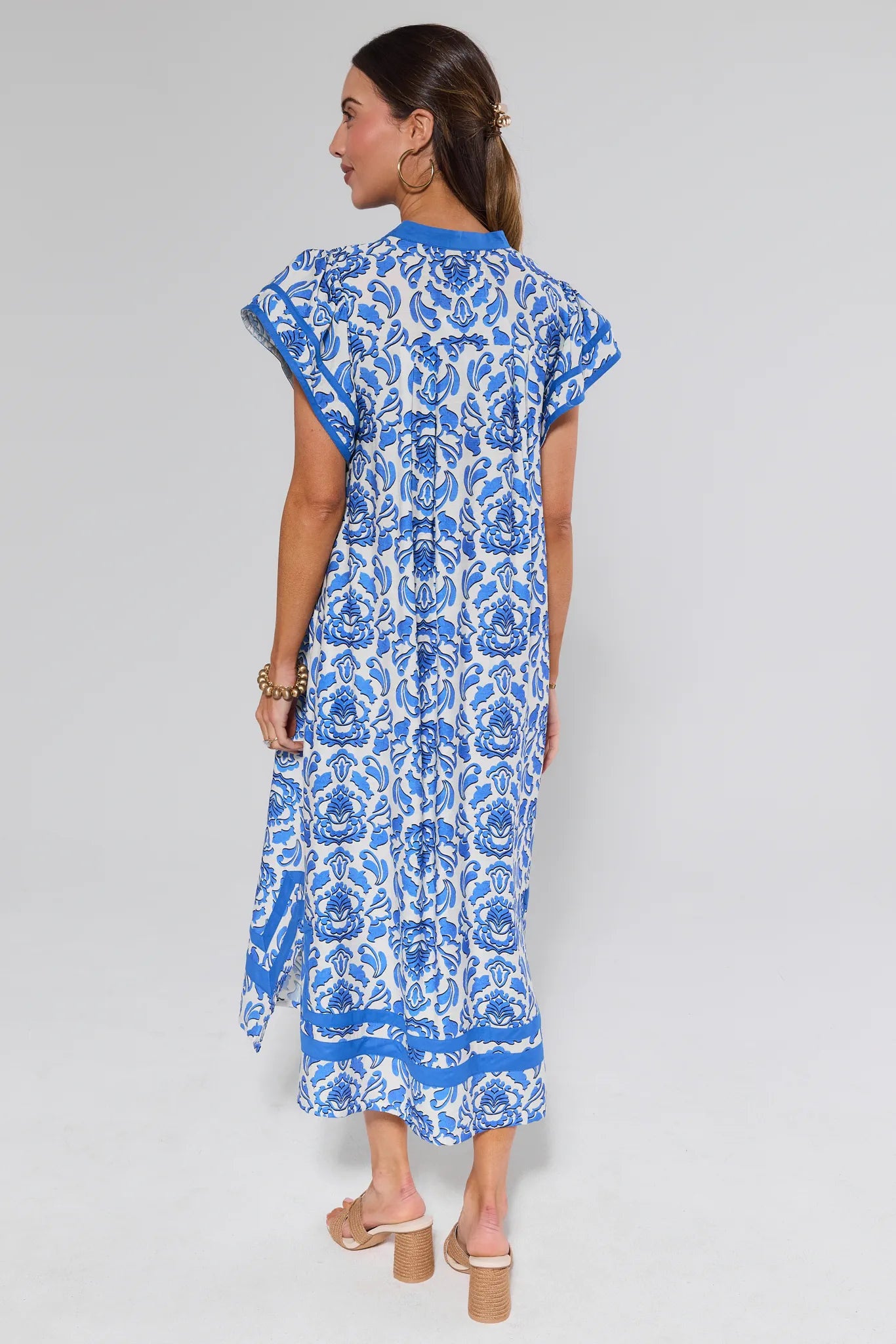 Woman wearing a blue and white patterned dress on a gray background