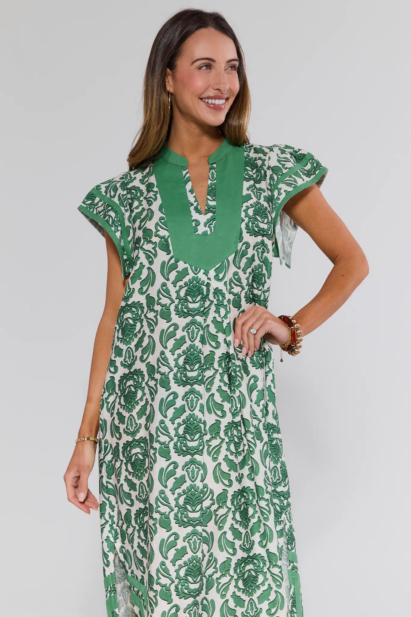 Woman wearing a green and white floral dress against a plain background