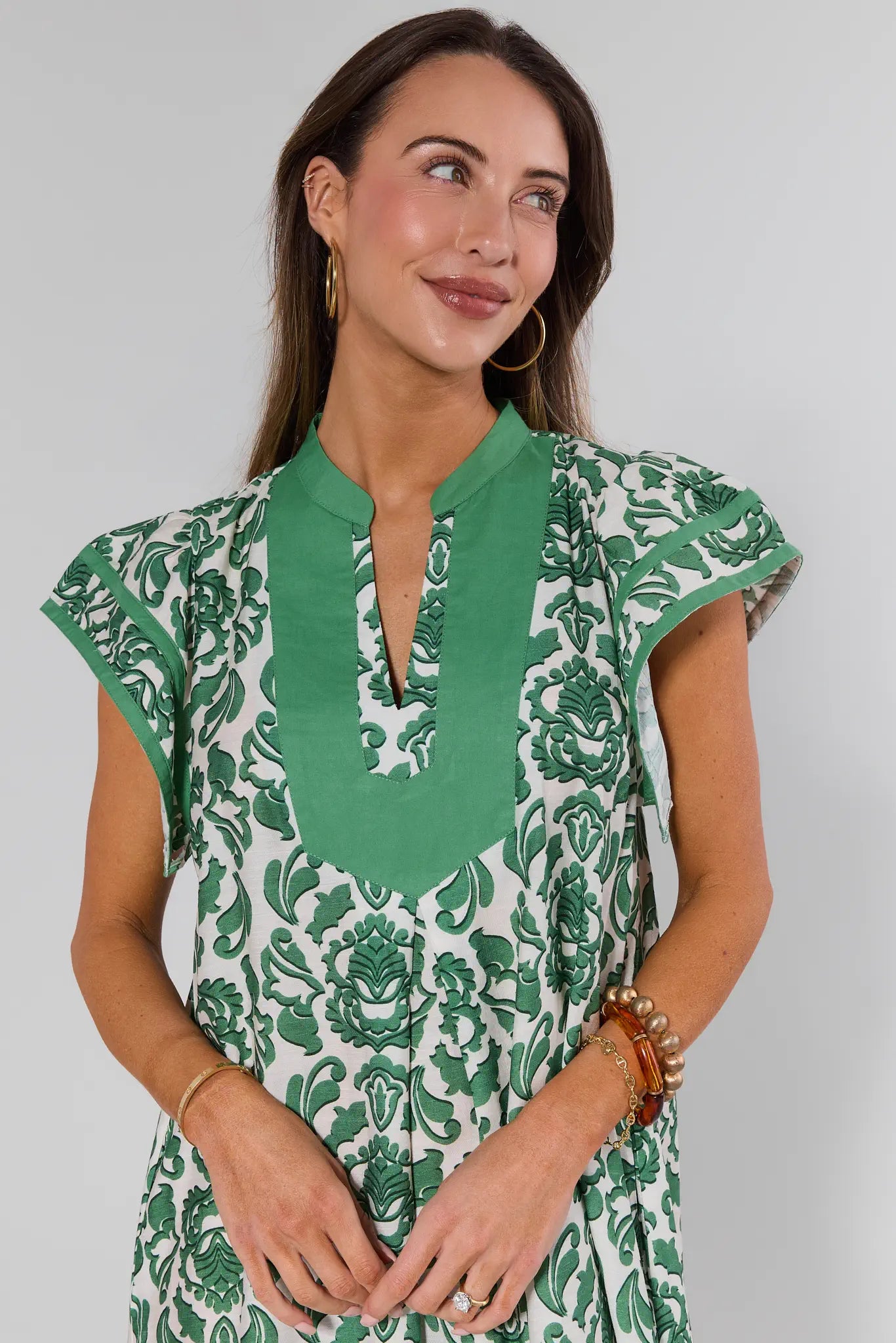 Woman wearing a green and white patterned dress against a plain background