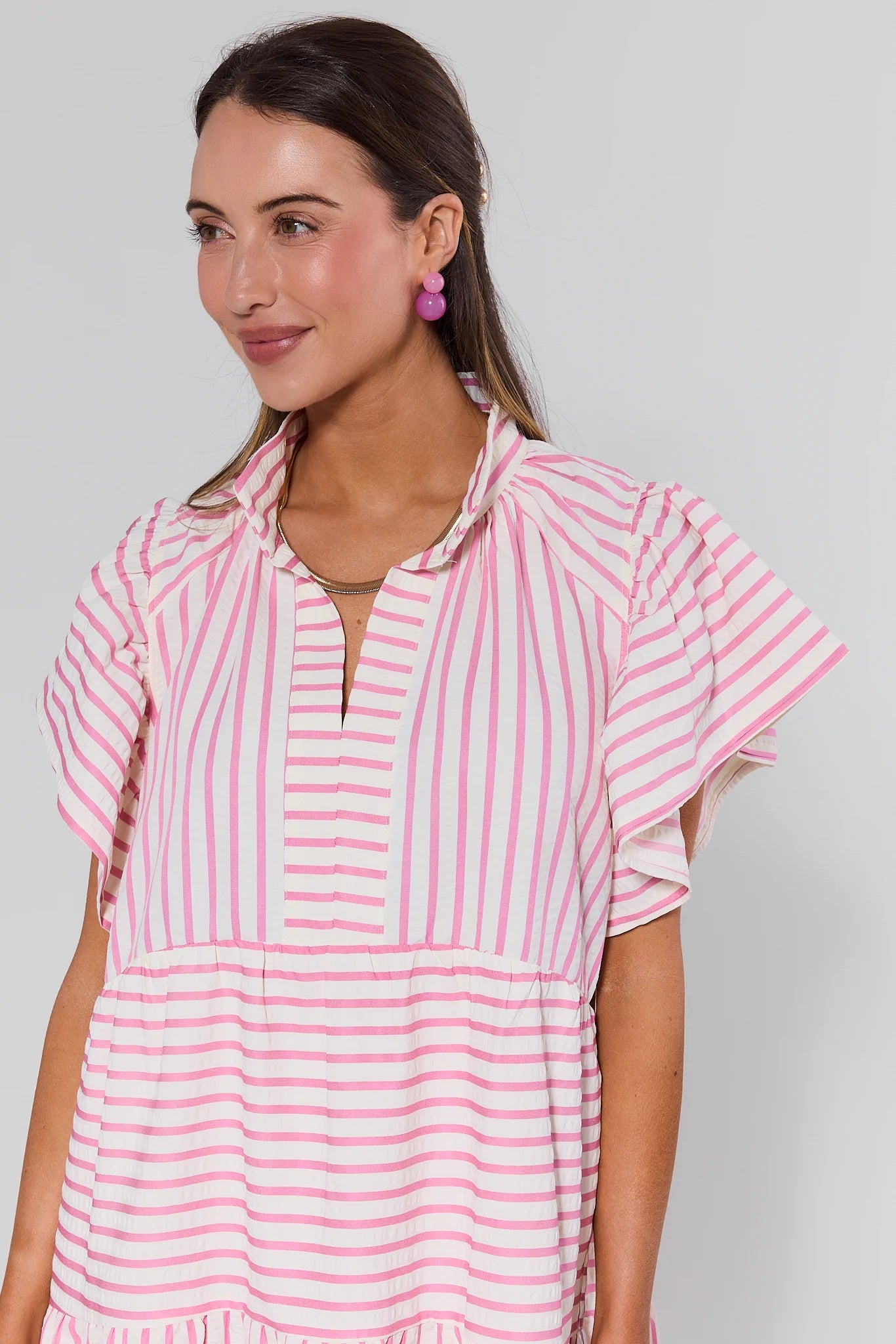 Woman wearing a pink and white striped dress against a plain background