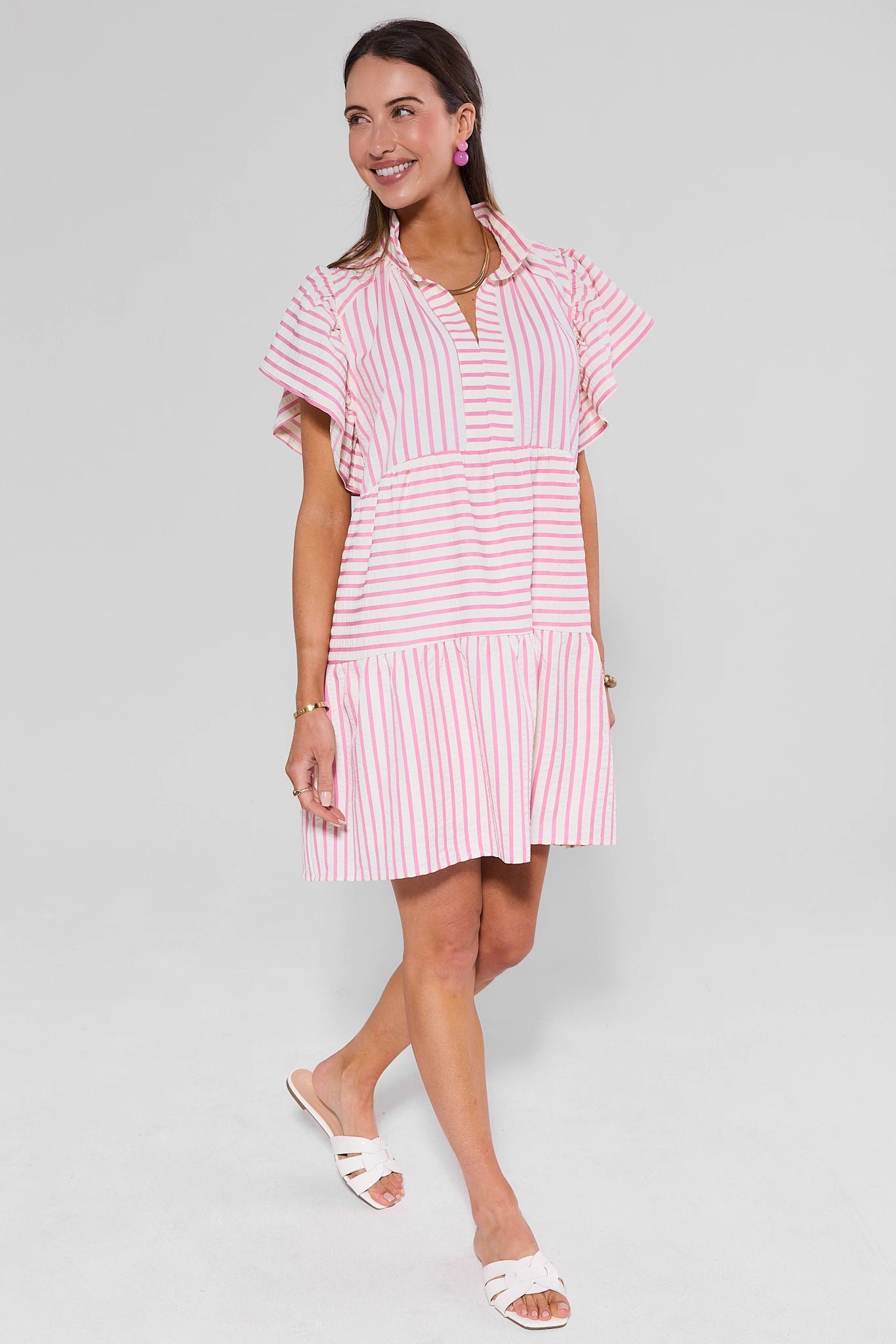 Woman wearing a pink and white striped dress on a gray background
