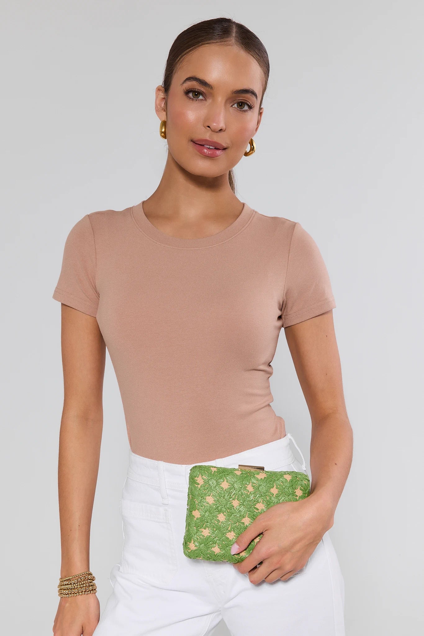 Woman holding a green clutch against a plain background