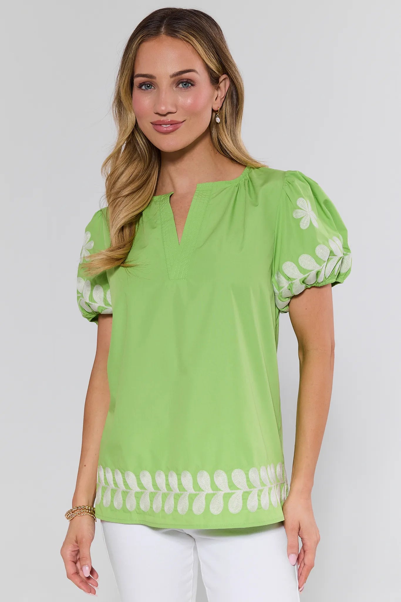 Woman wearing a green blouse with white patterns on a plain background