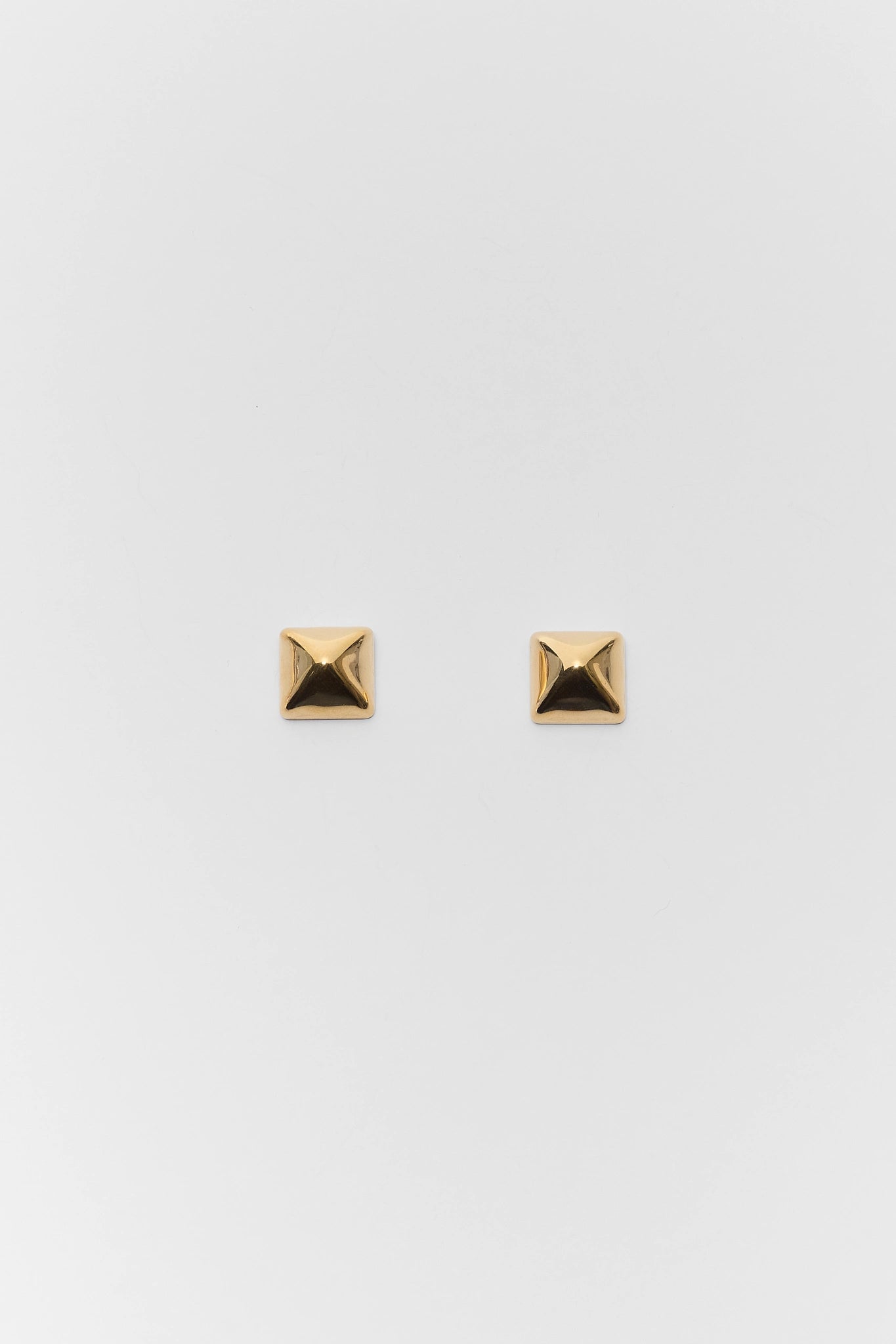 Gold square stud earrings on a light gray background