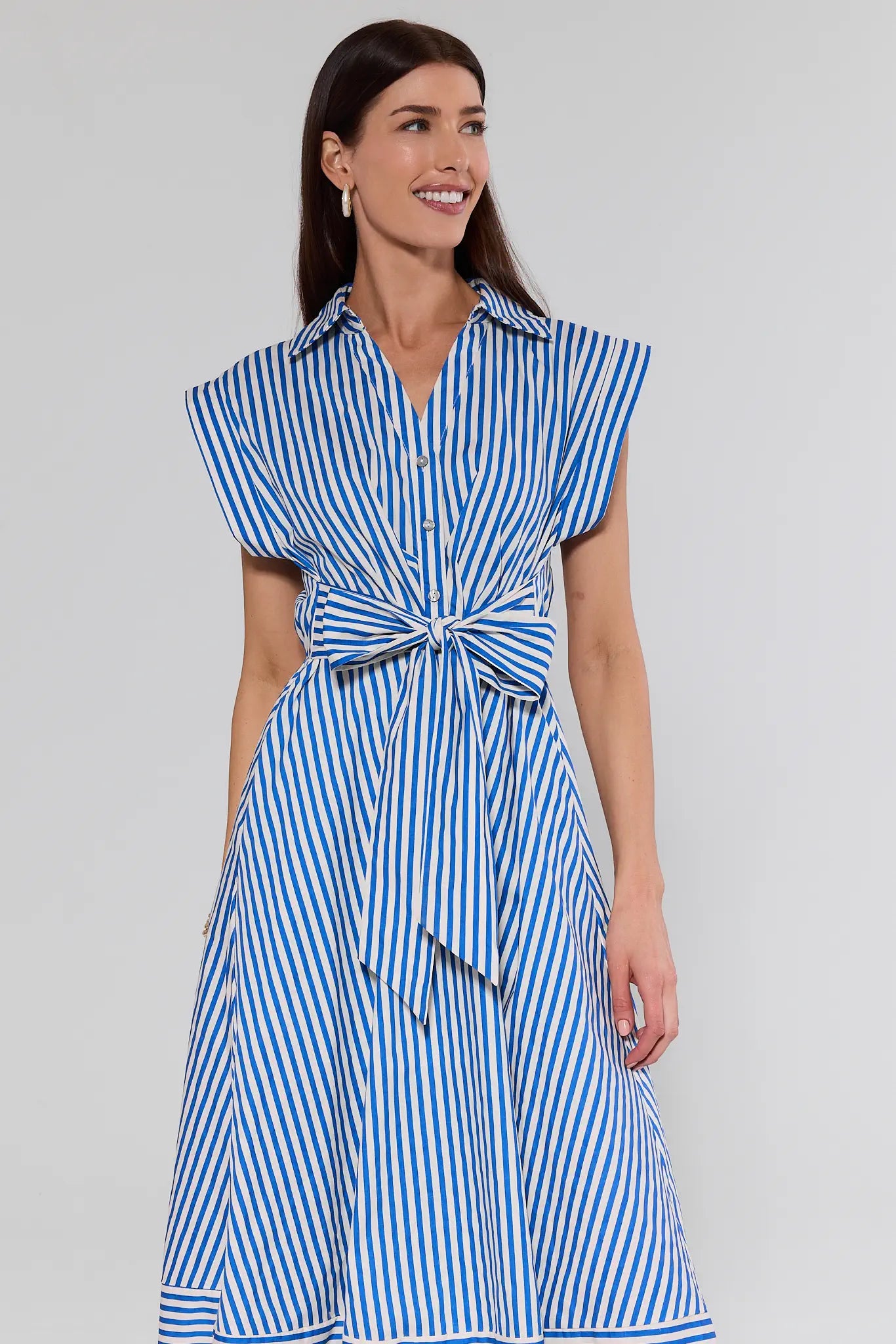 Woman wearing a blue and white striped dress against a plain background