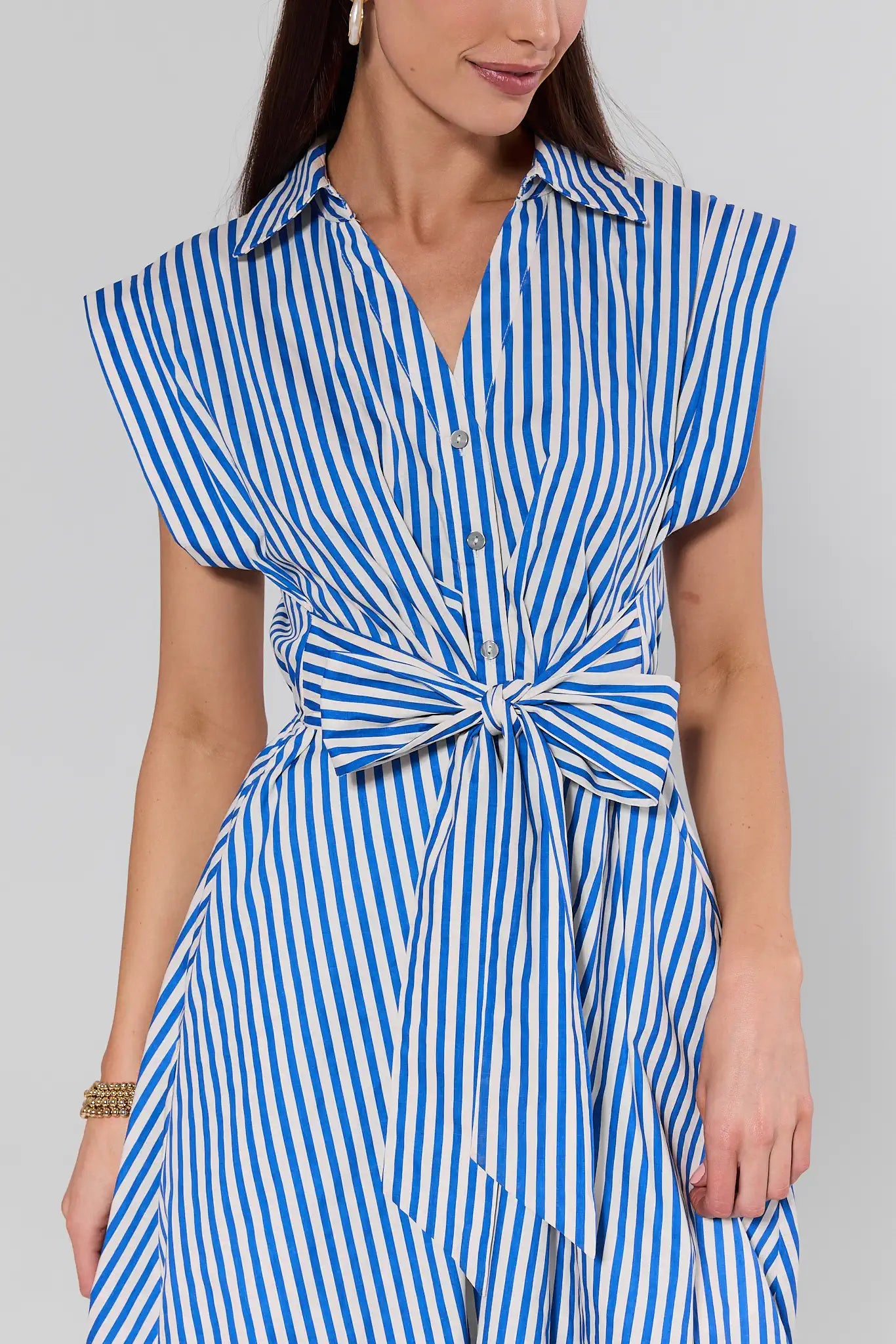 Woman wearing a blue and white striped dress against a gray background