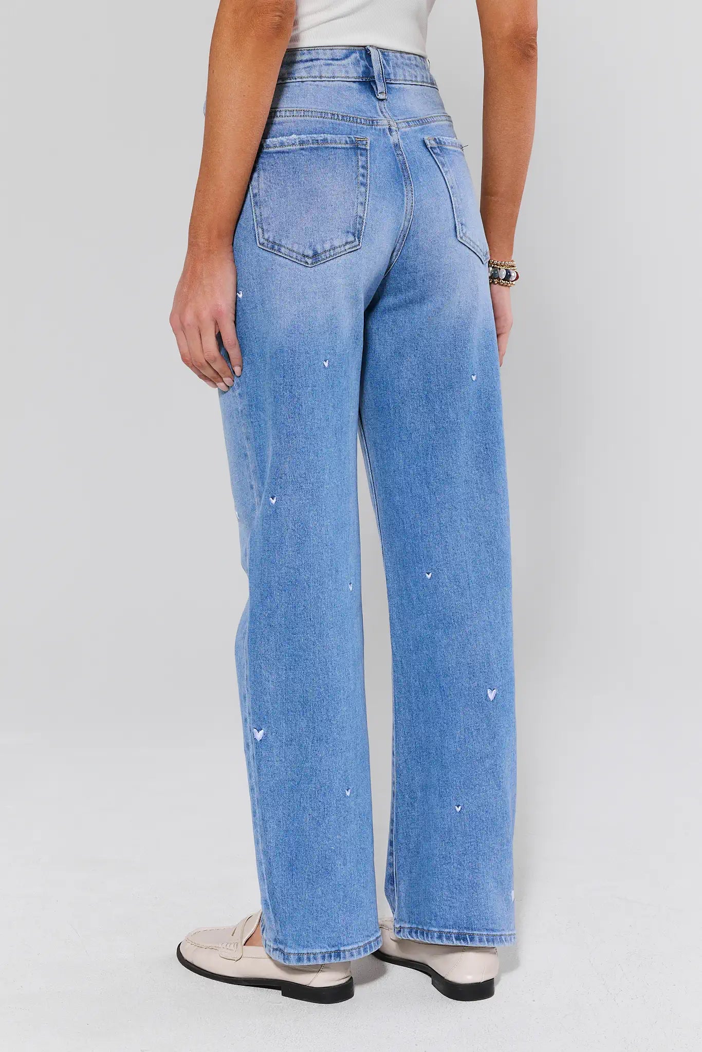 Person wearing light blue jeans on a plain background