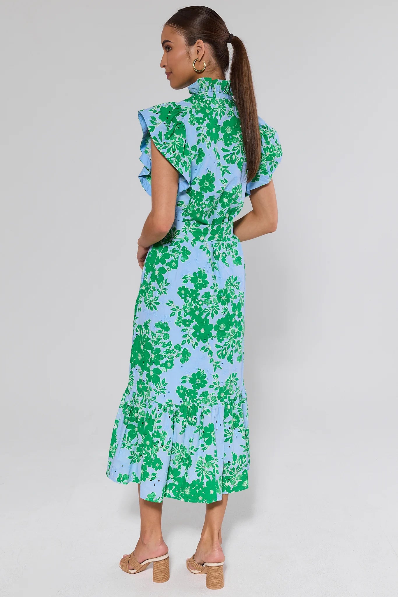 Woman wearing a floral dress with green and blue pattern on a white background