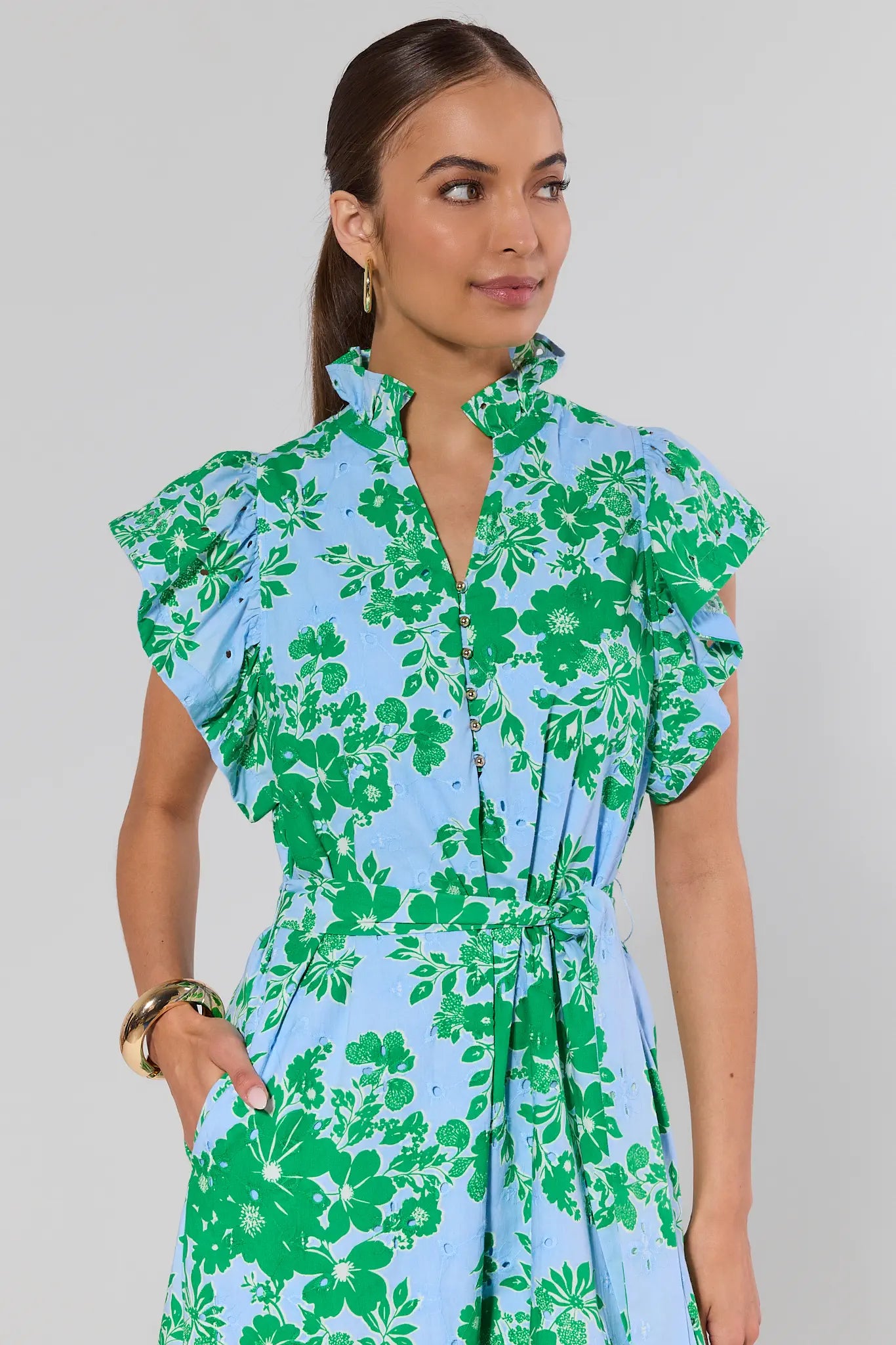 Woman wearing a green and blue floral dress on a gray background