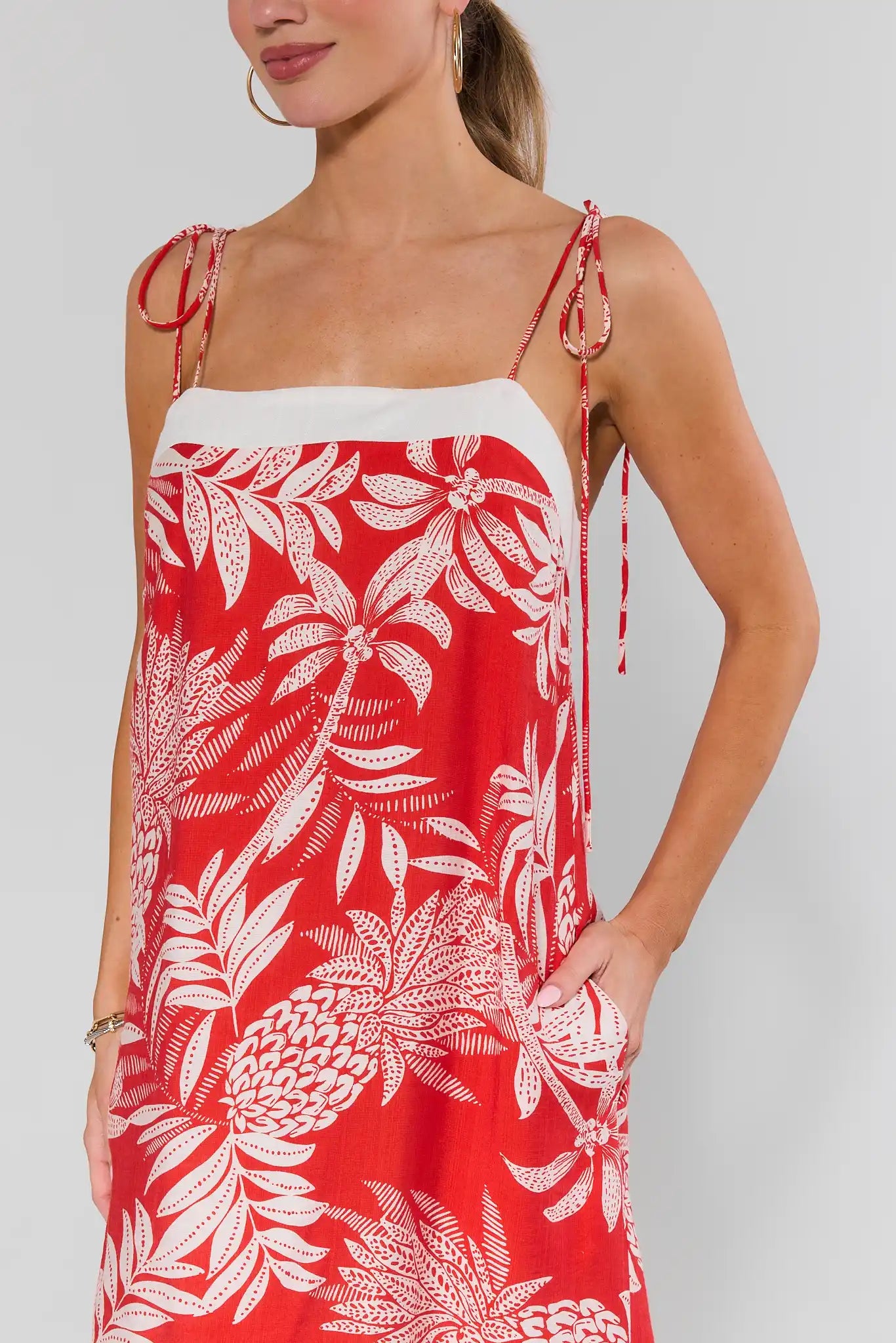 close up Woman wearing a red dress with white floral patterns on a plain background