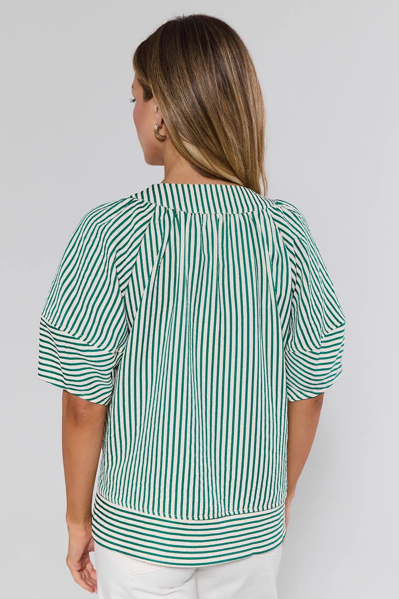 Woman wearing a green and white striped blouse against a plain background