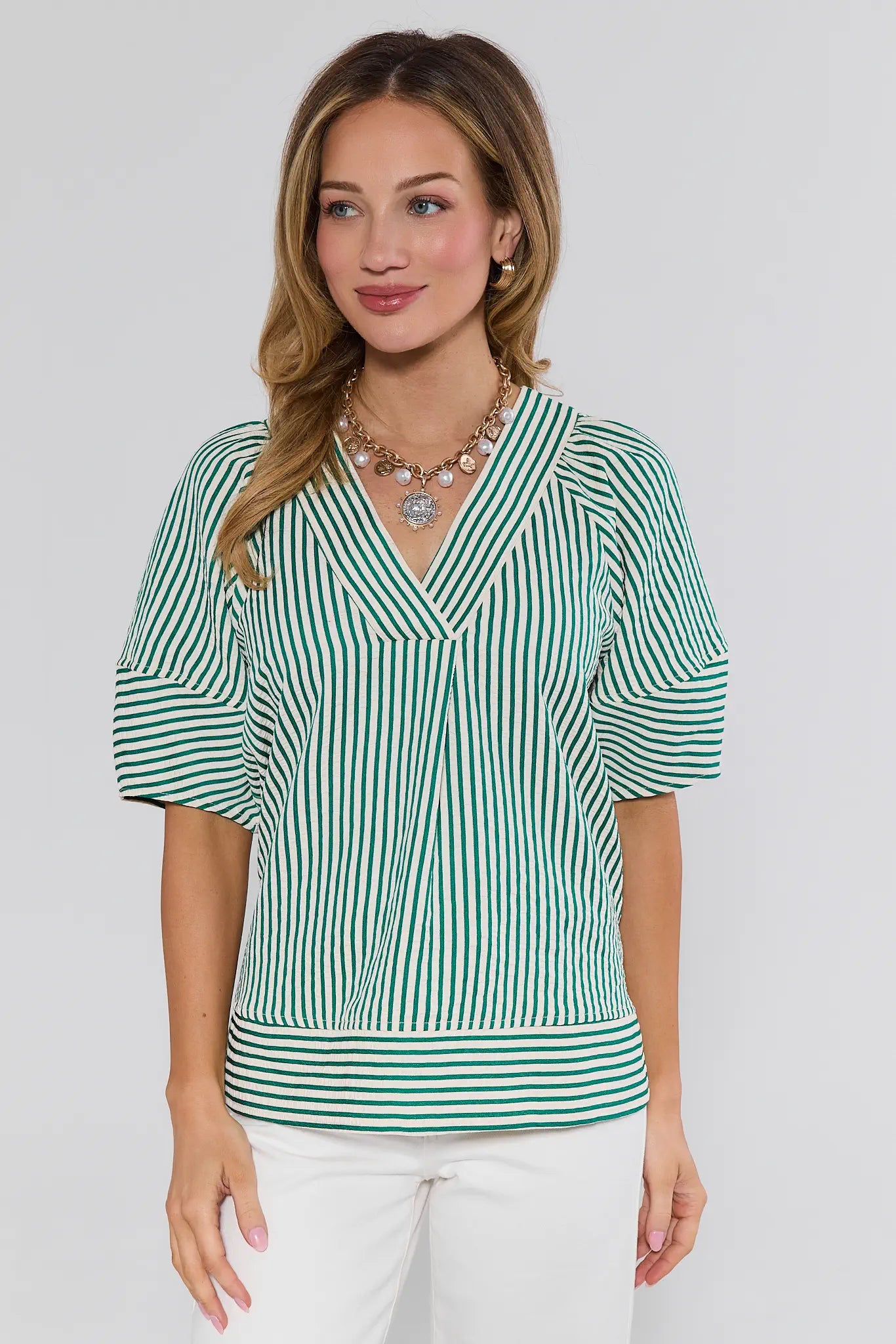 Woman wearing a green and white striped blouse against a plain background