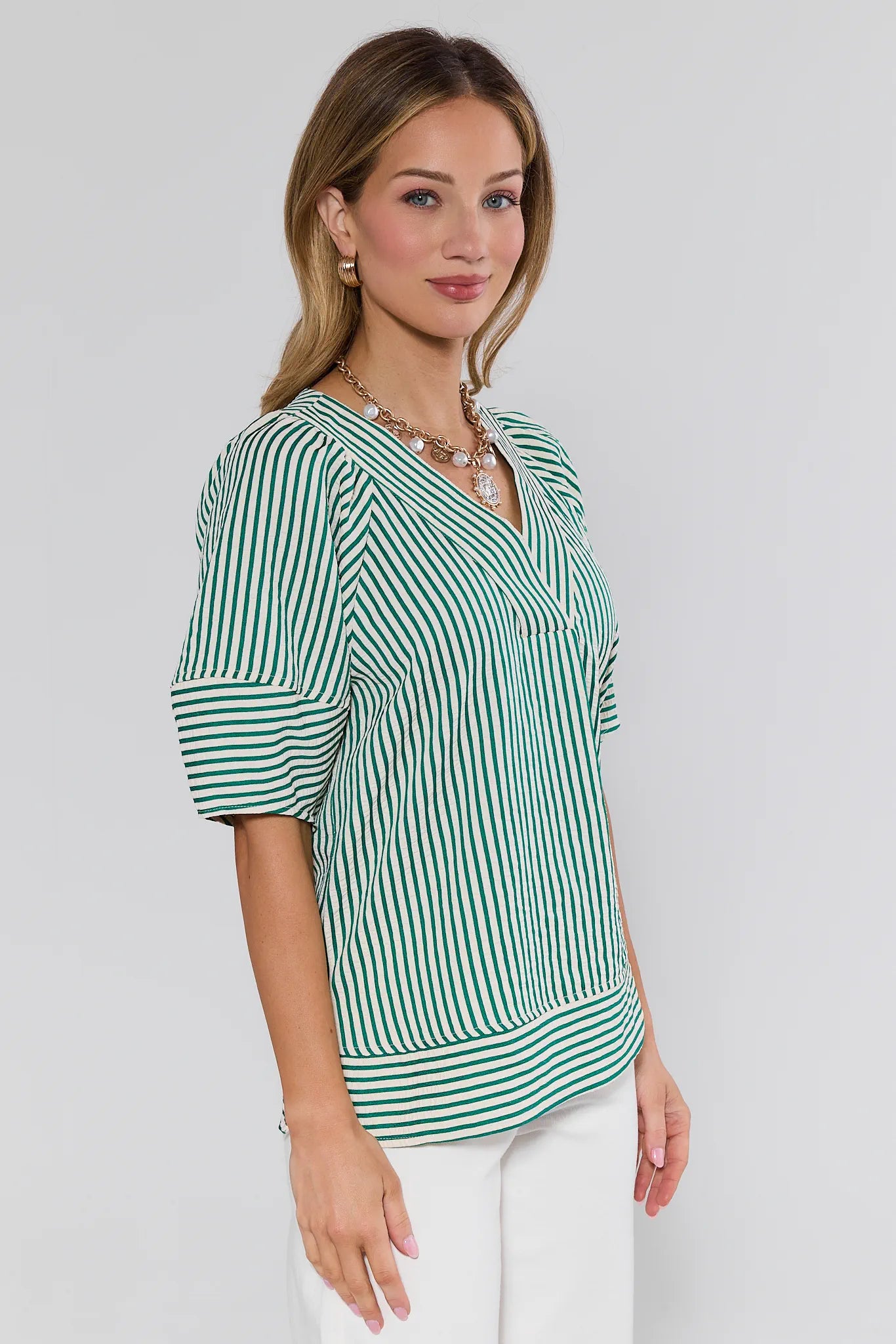 Woman wearing a green and white striped blouse against a plain background