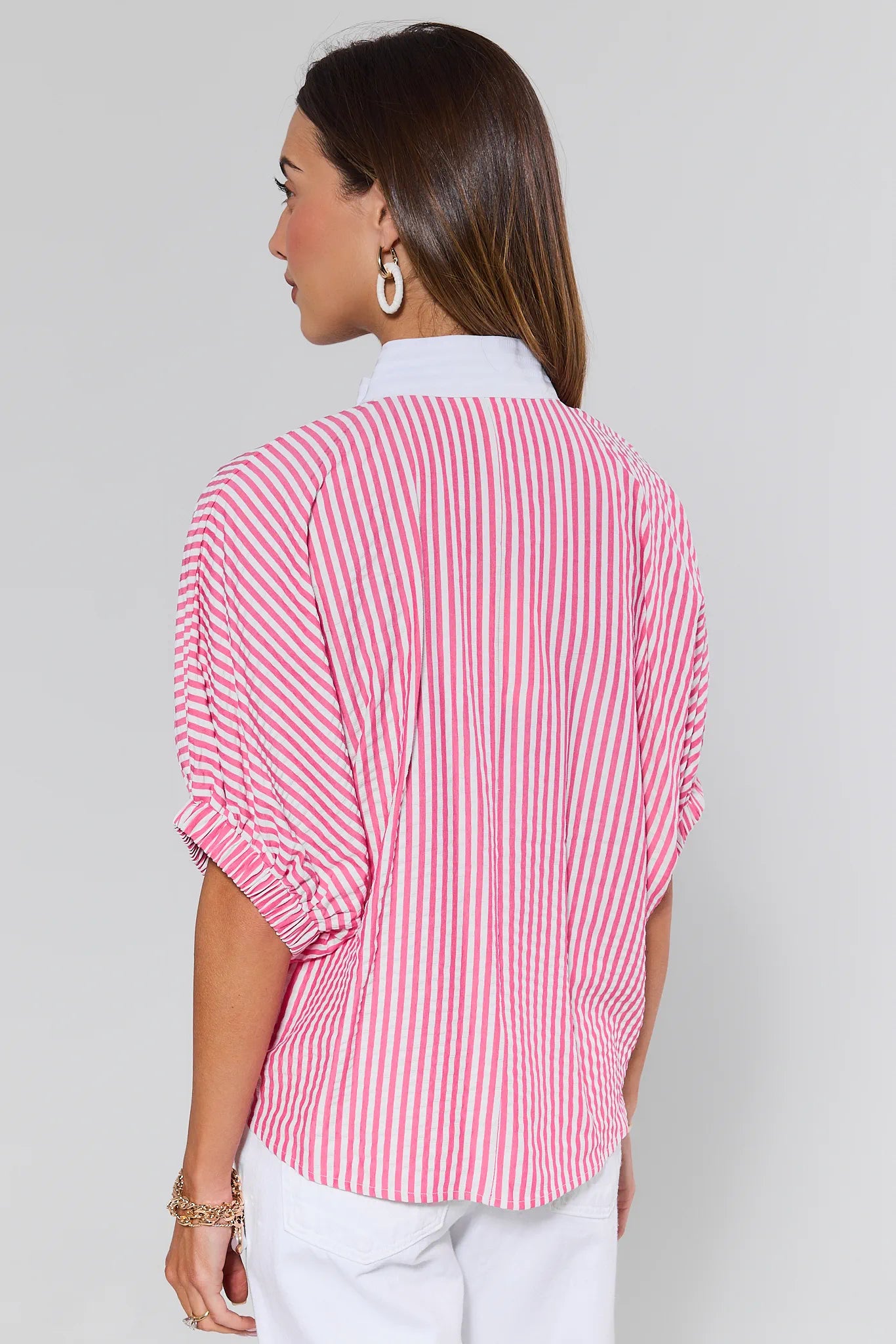 Woman wearing a pink and white striped shirt against a plain background