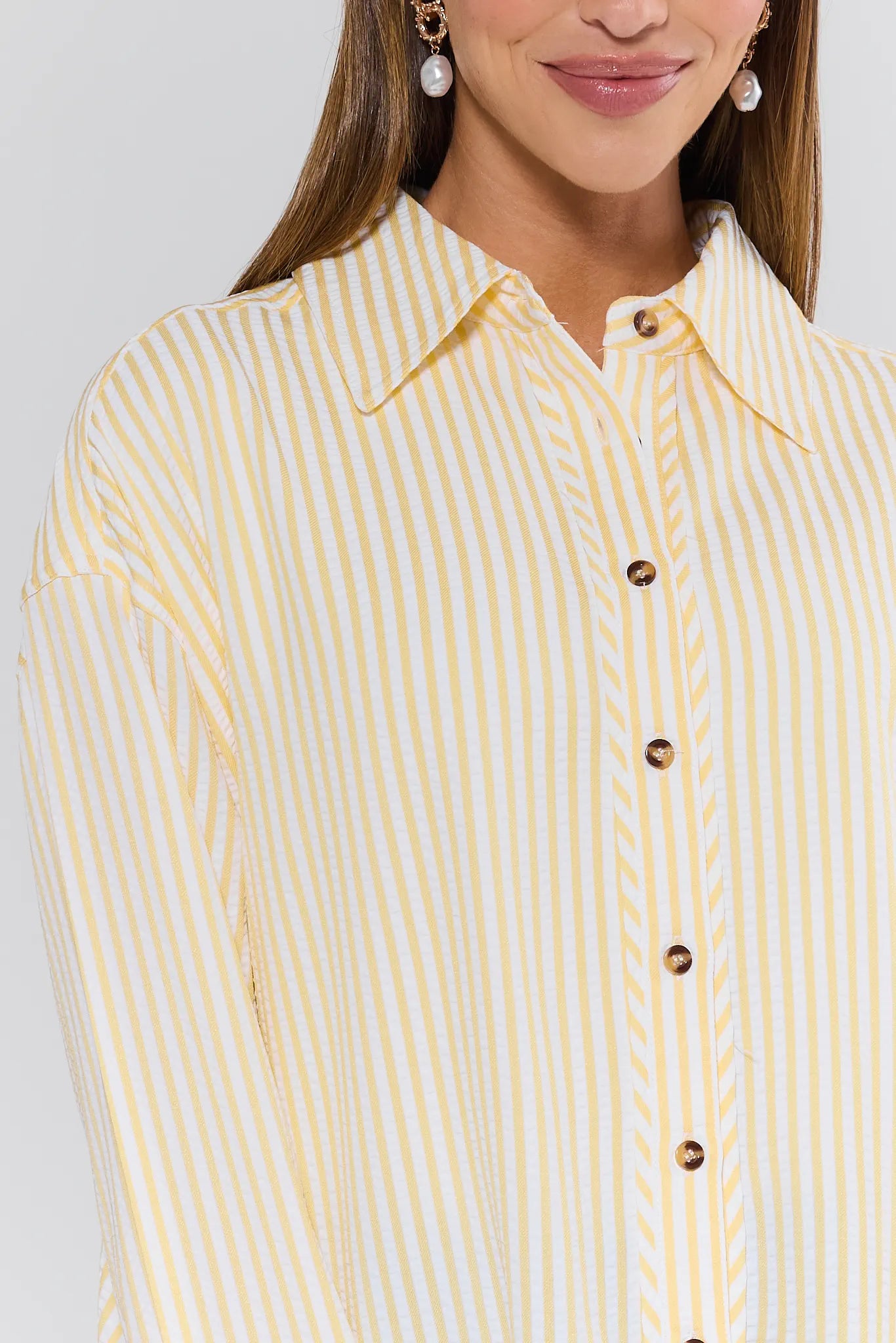 Woman wearing a yellow and white striped shirt with a plain background
