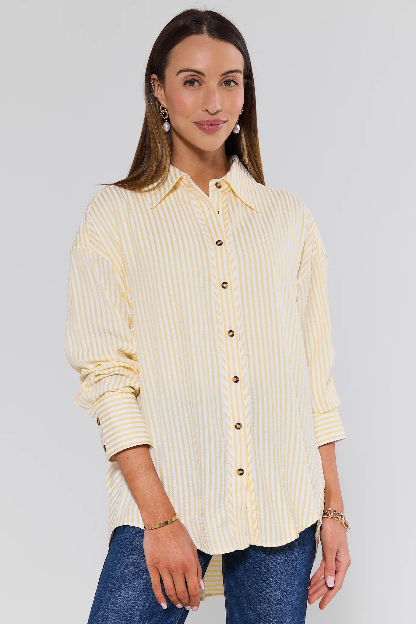 Woman wearing a yellow striped shirt with a plain background