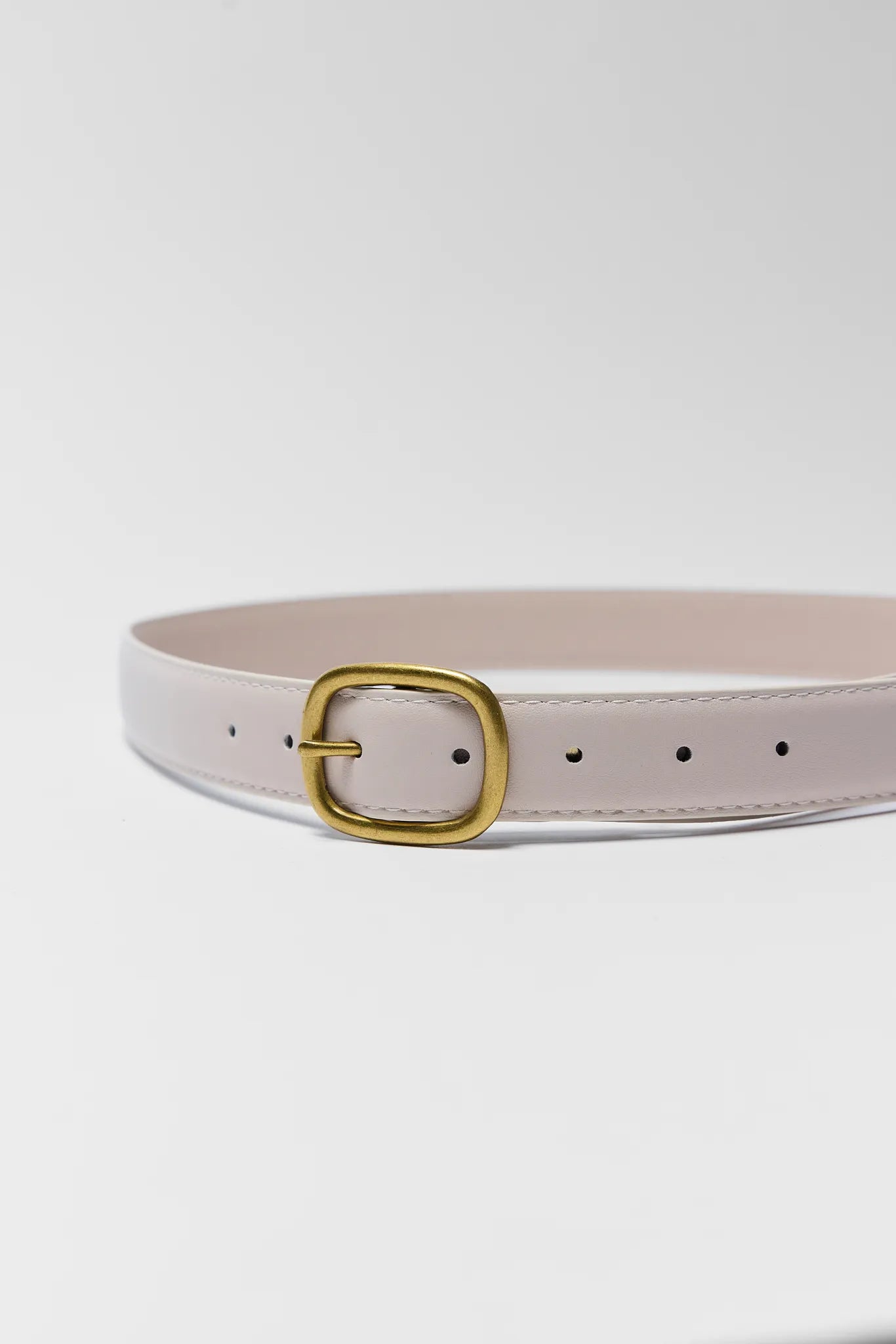 Light pink belt with a gold buckle on a light gray background