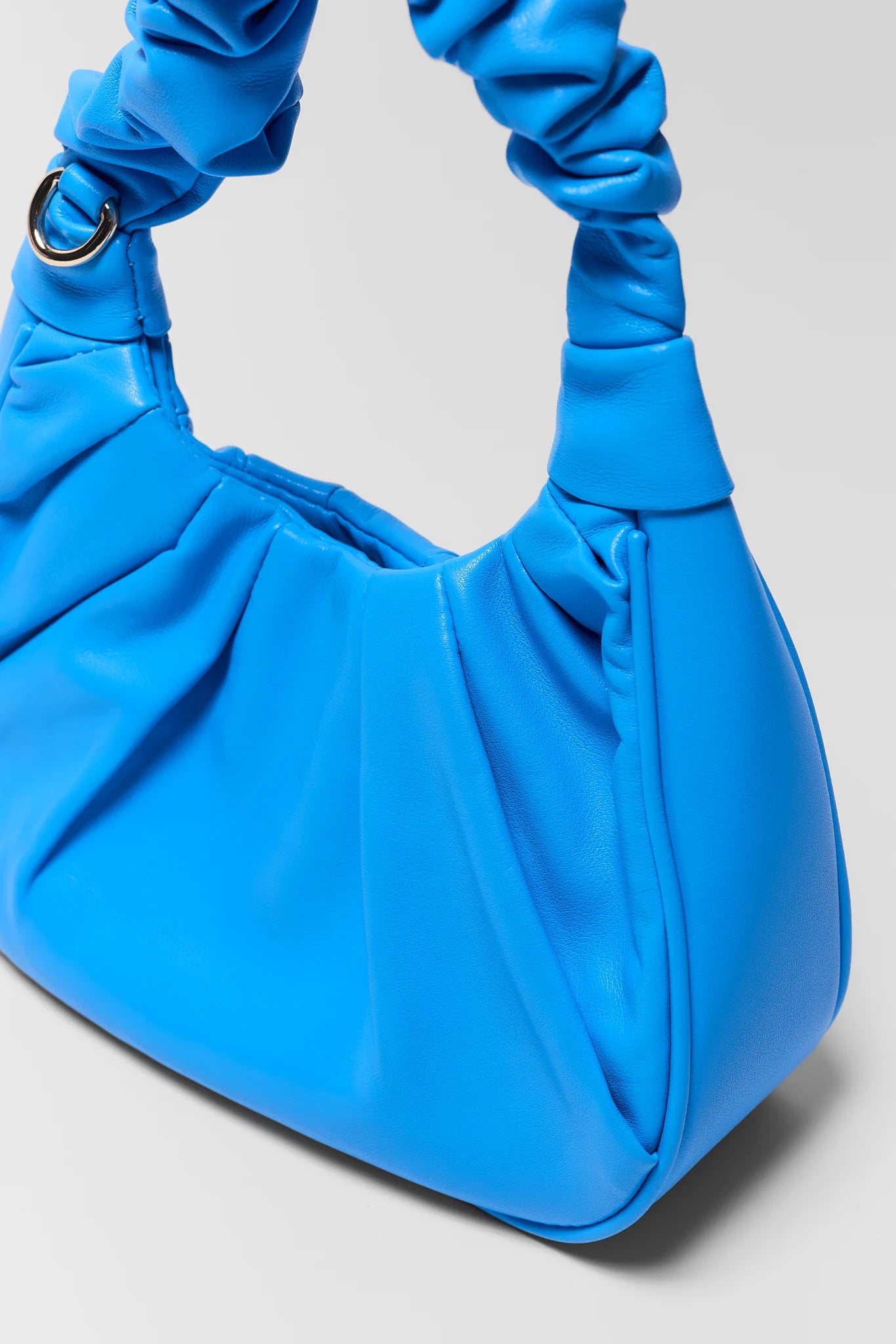 Blue handbag with matching blue gloves on a light gray background