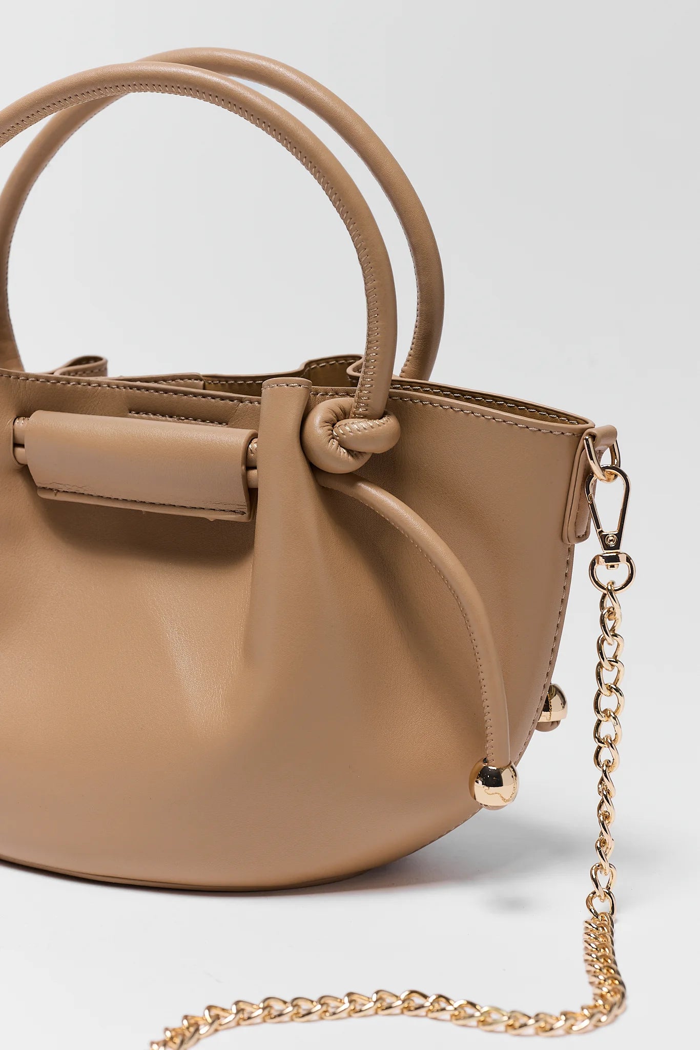 Beige handbag with a gold chain on a light gray background