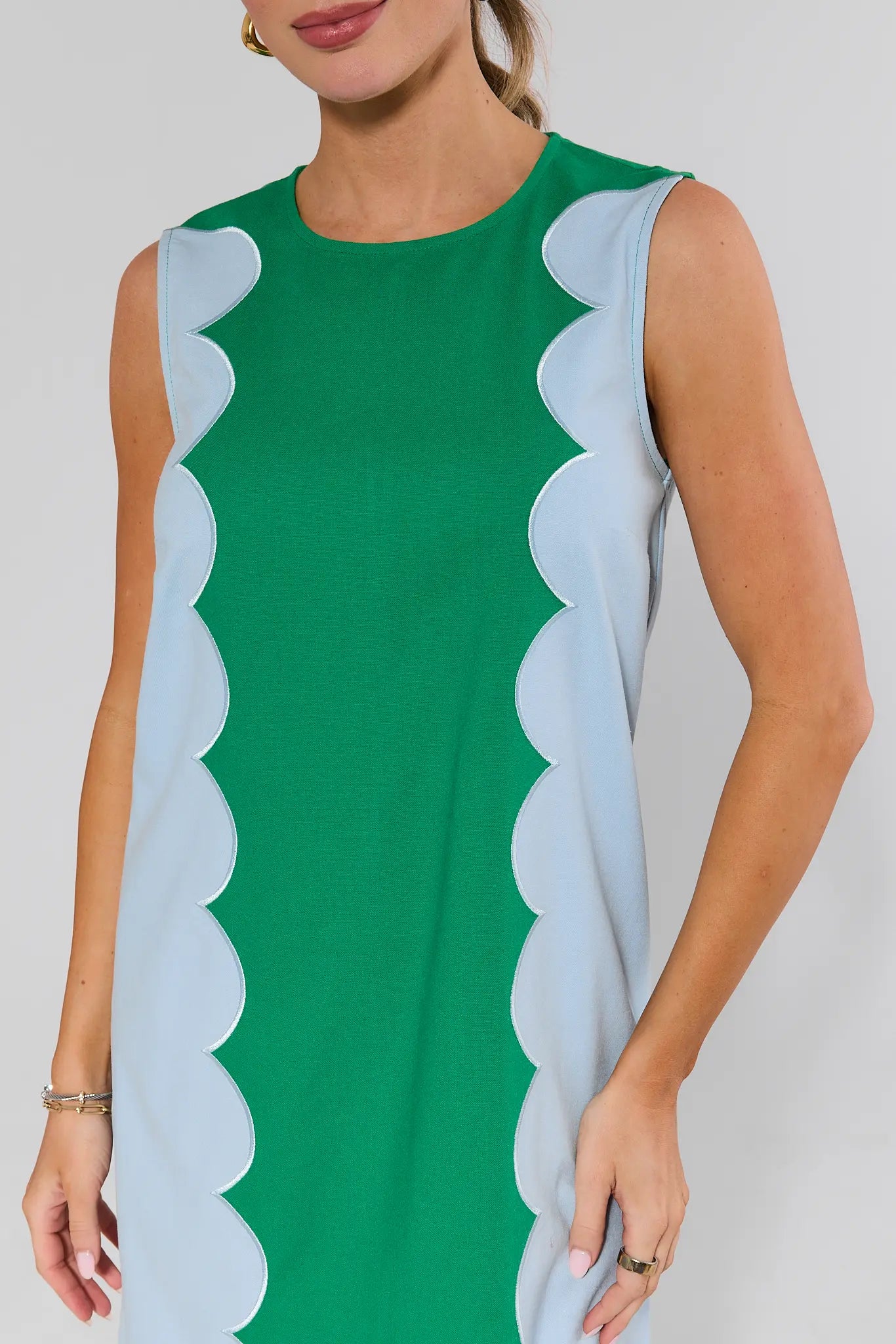 close up Green dress with scalloped light blue trim worn by a model on a white background