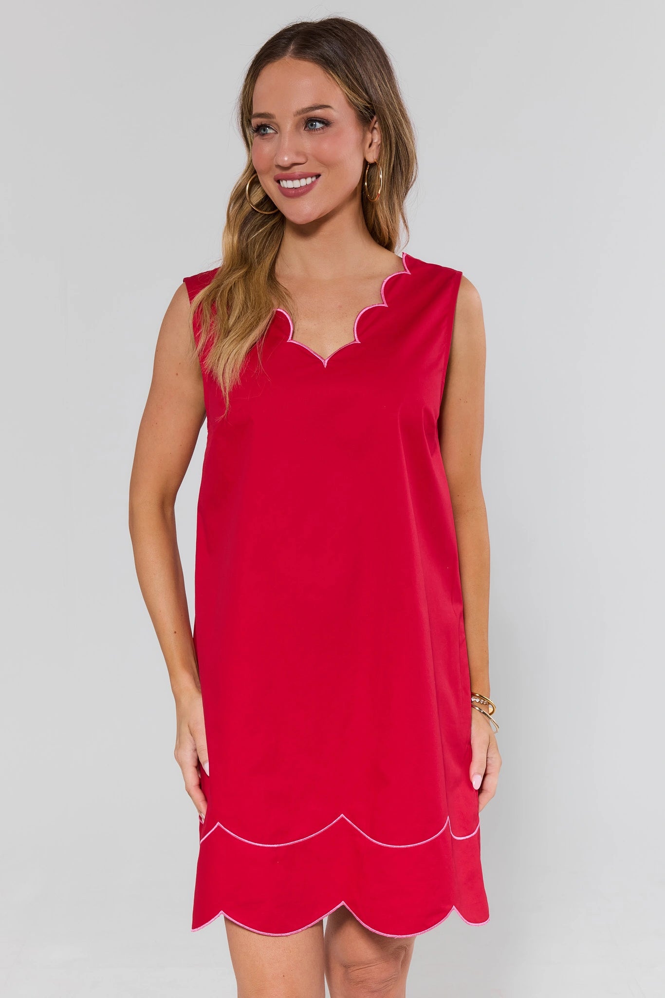 Woman wearing a red dress with white trim on a plain background