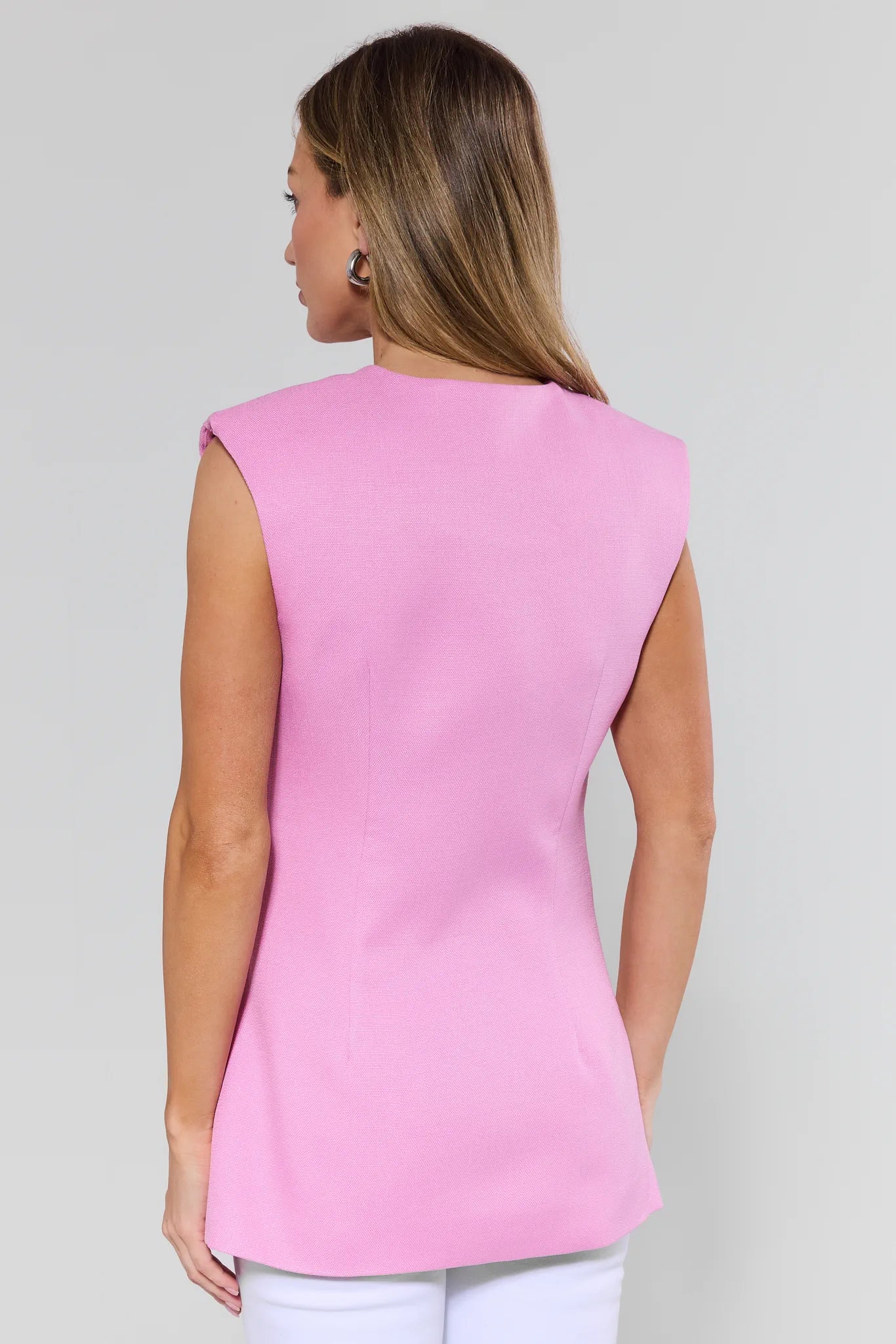 Woman wearing a pink sleeveless top against a plain background