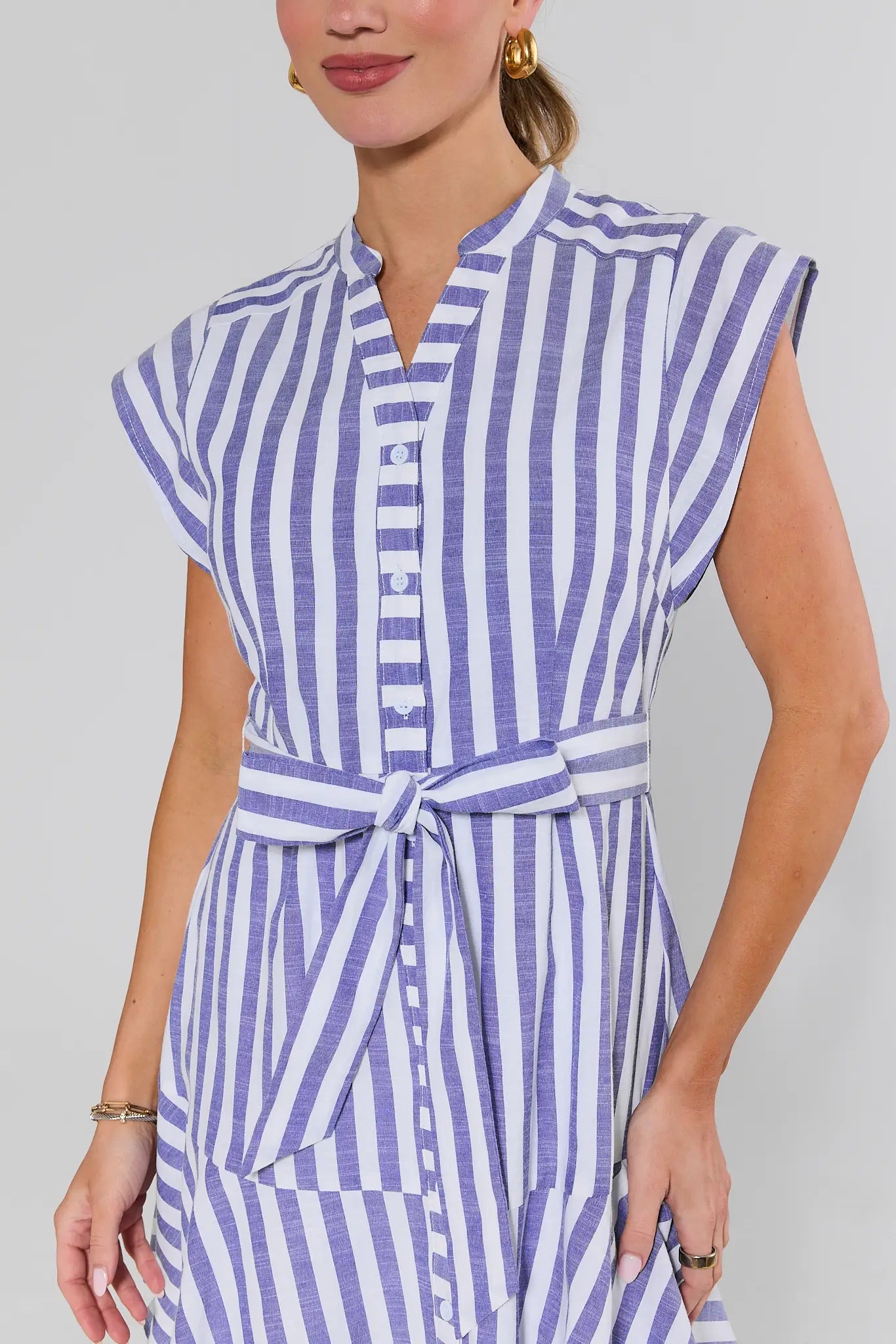 close up Woman wearing a blue and white striped dress against a gray background