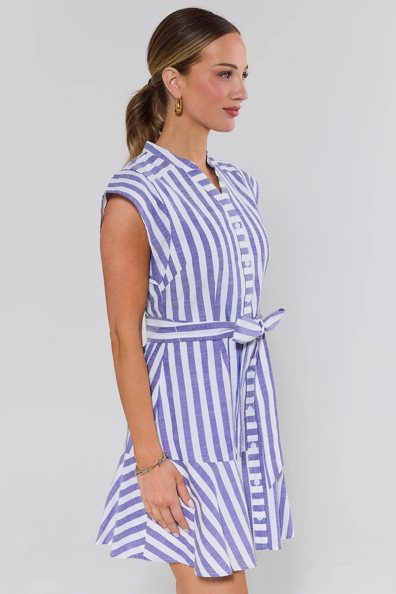 side shot Woman wearing a blue and white striped dress on a gray background