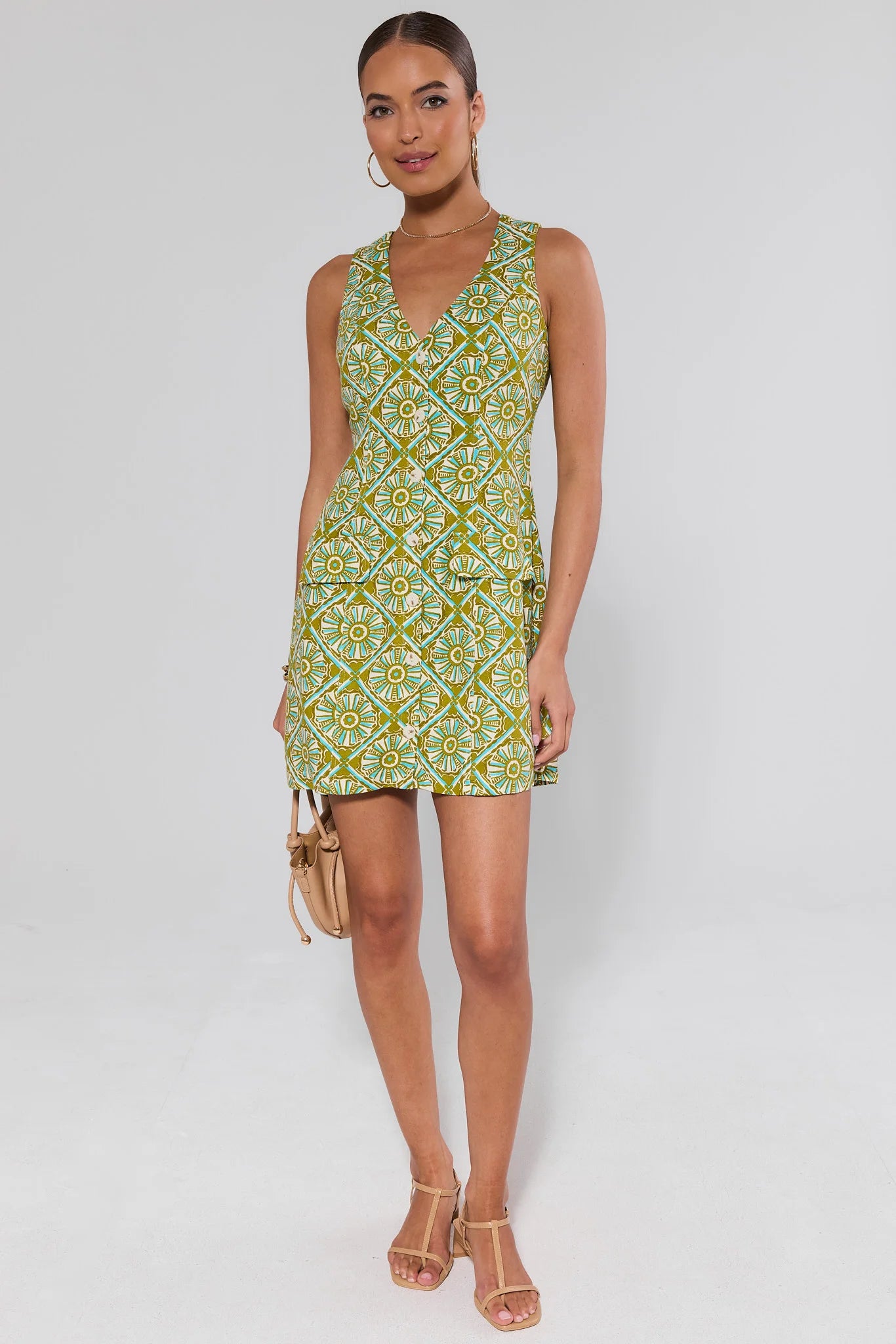 Woman wearing a green patterned seraphina dress on a white background