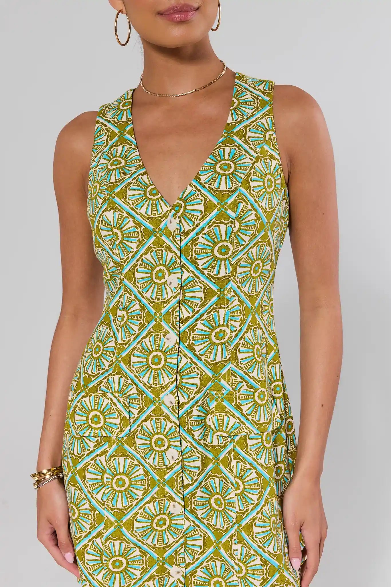 close up Woman wearing a green and blue patterned dress on a plain background