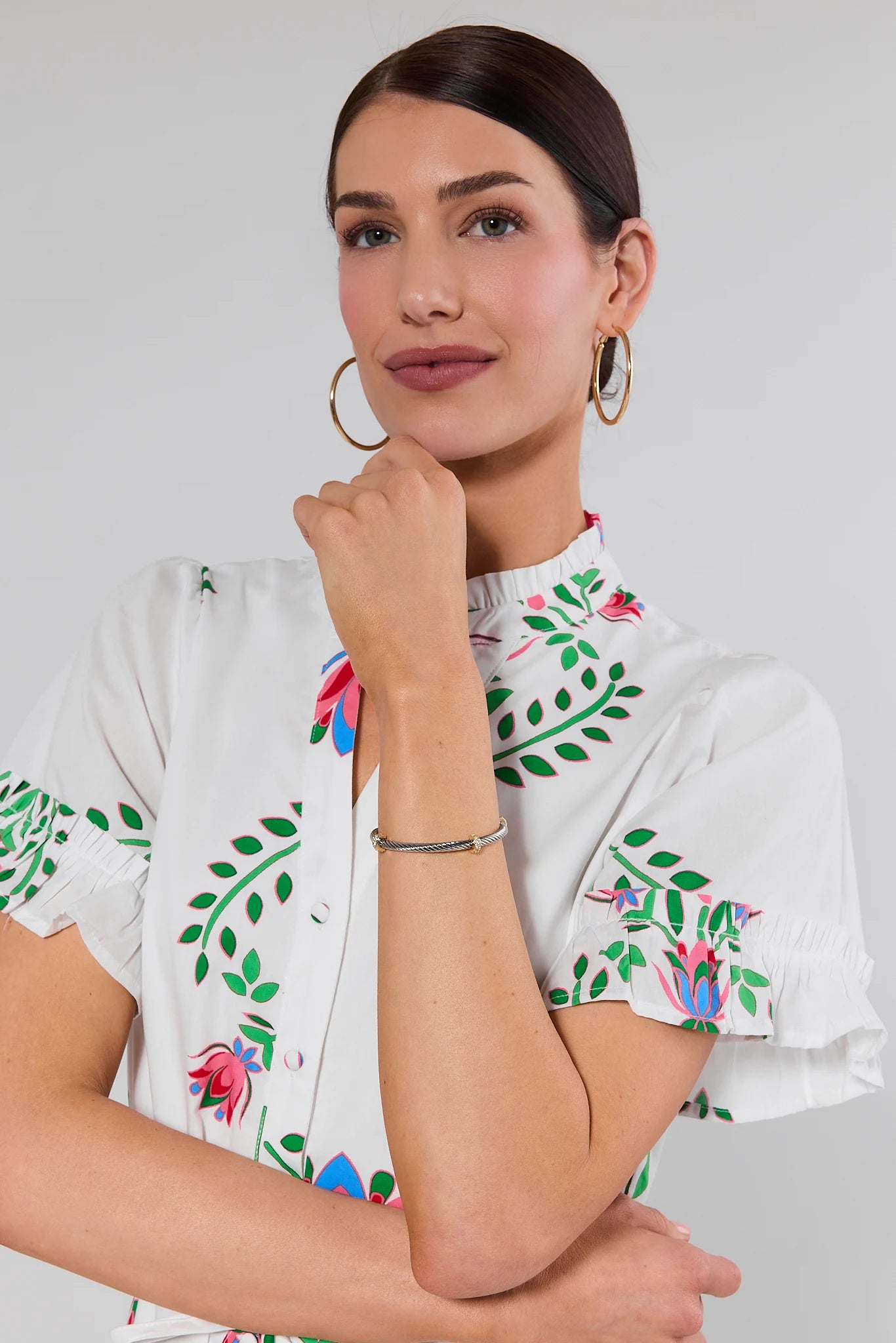 Woman wearing a white blouse with floral embroidery on a plain background