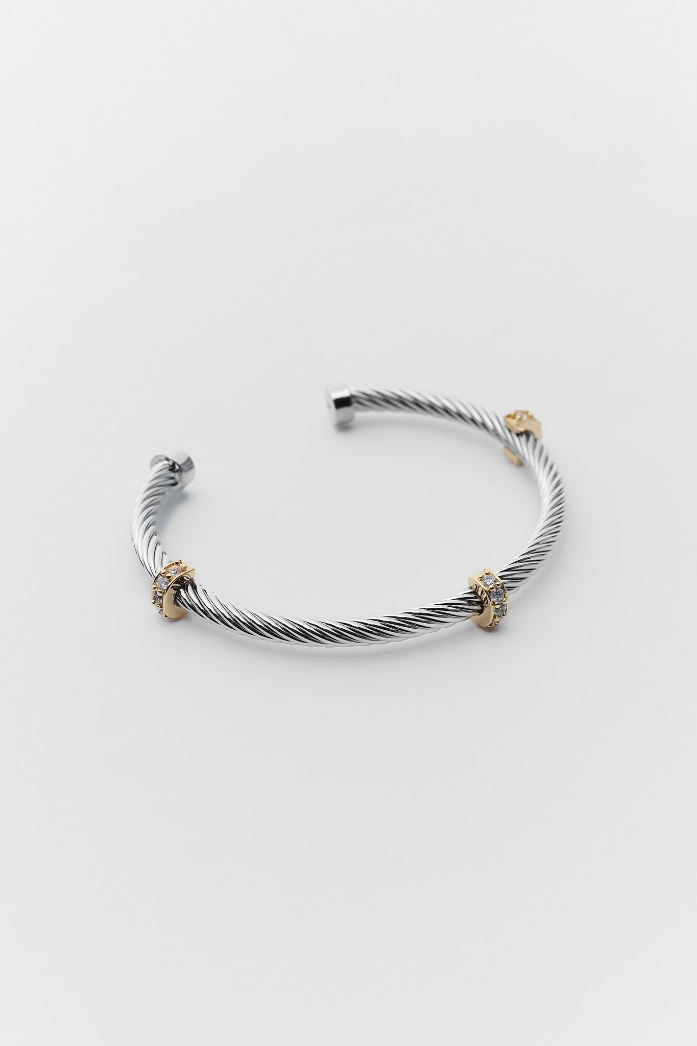 Silver cable bracelet with gold accents on a white background