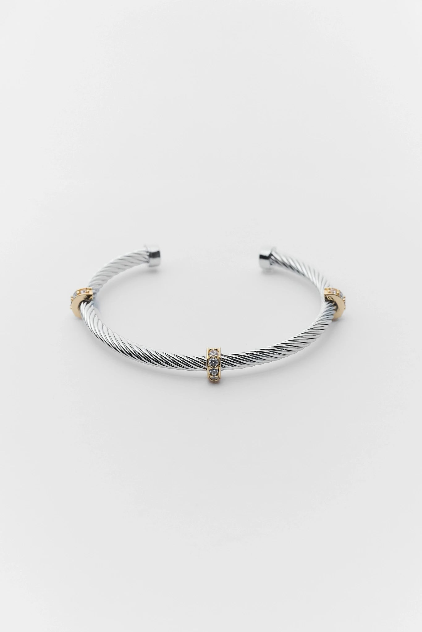 Silver cable bracelet with gold accents on a light gray background