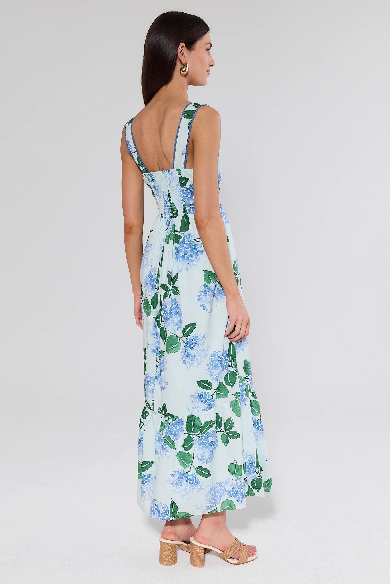 Woman wearing a floral dress with blue flowers on a plain background