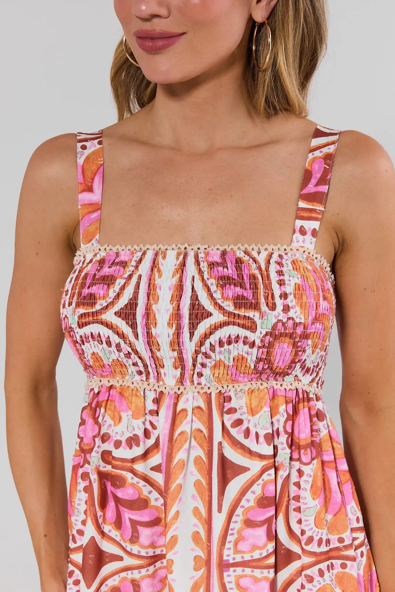 close up Woman wearing a sleeveless dress with a pink and orange pattern on a plain background