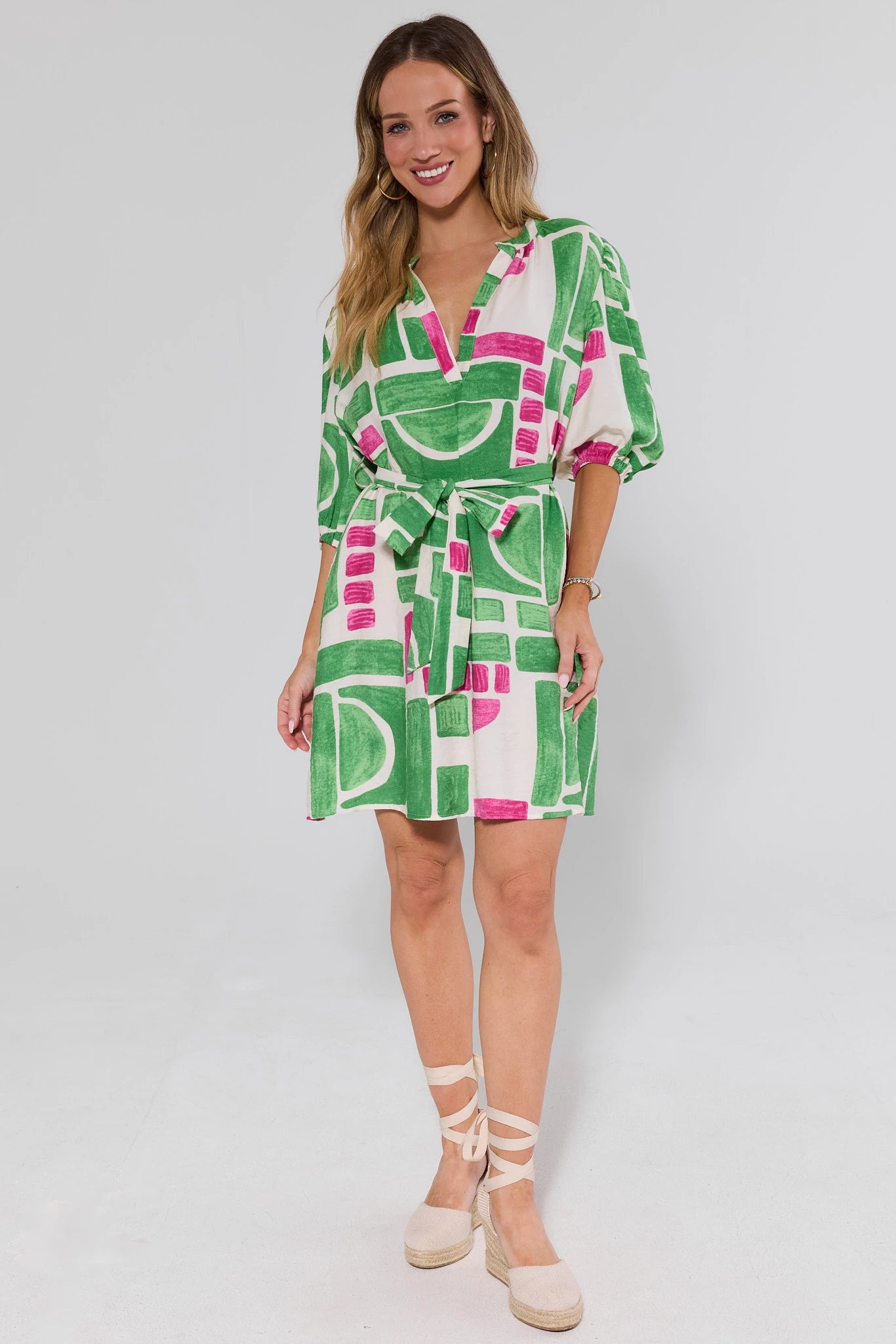Woman wearing a green and pink patterned barbara dress on a white background