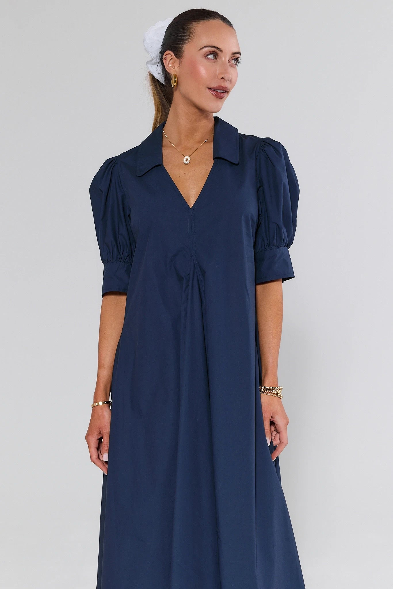 Woman wearing a navy blue dress with puff sleeves against a white background