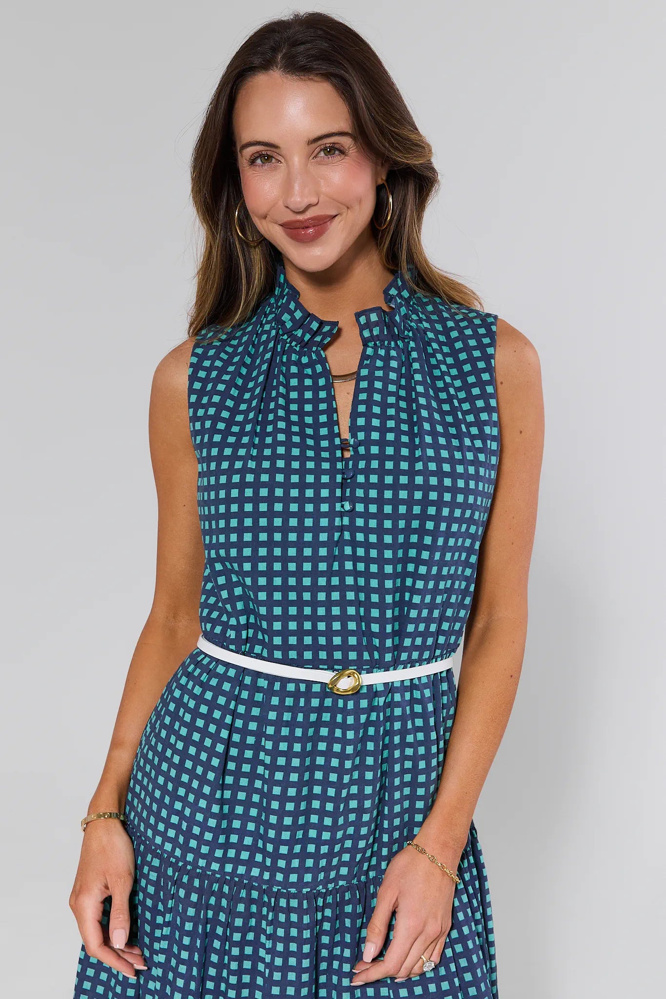 Woman wearing a blue checkered dress with a white belt against a plain background