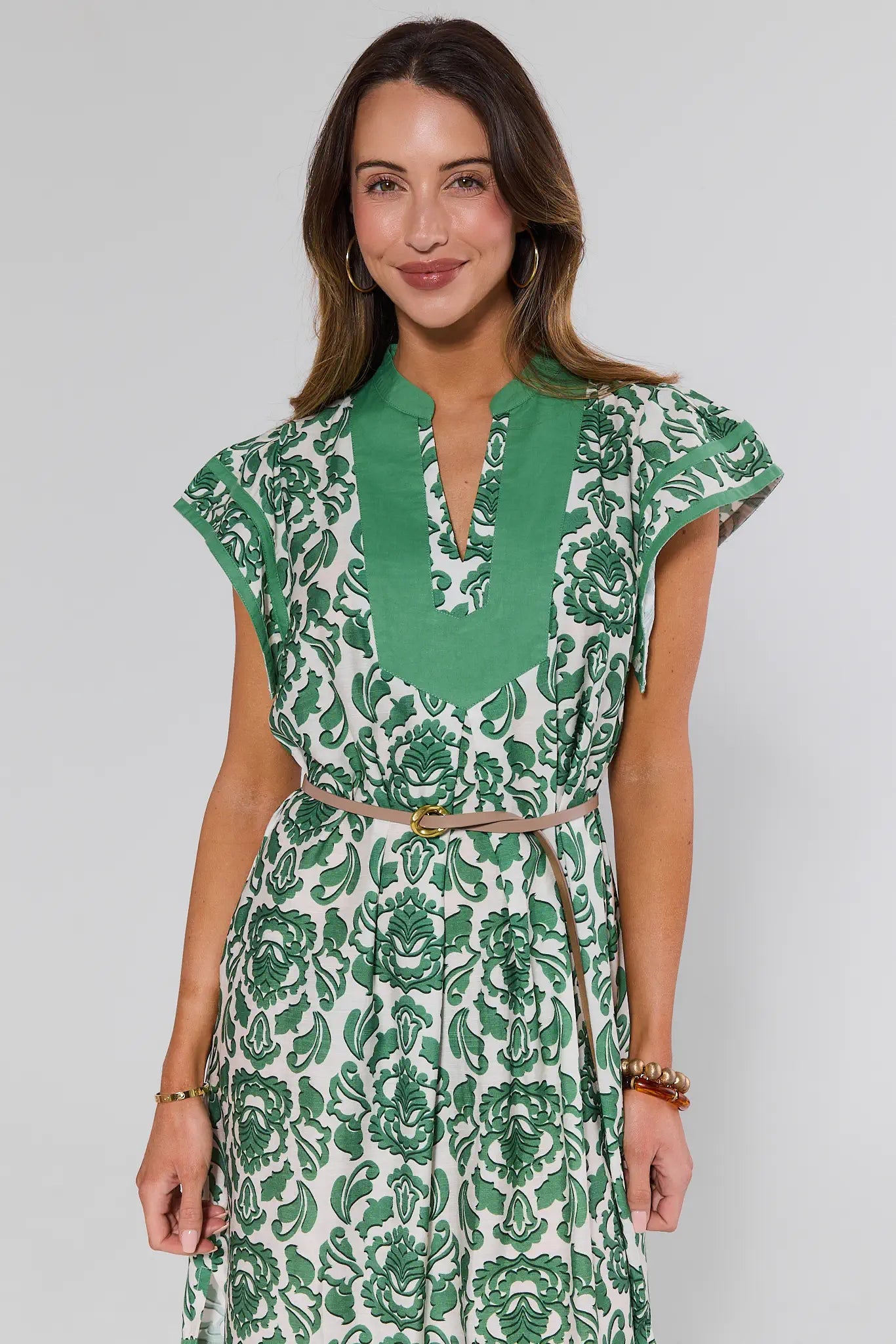 Woman wearing a green and white floral dress on a plain background