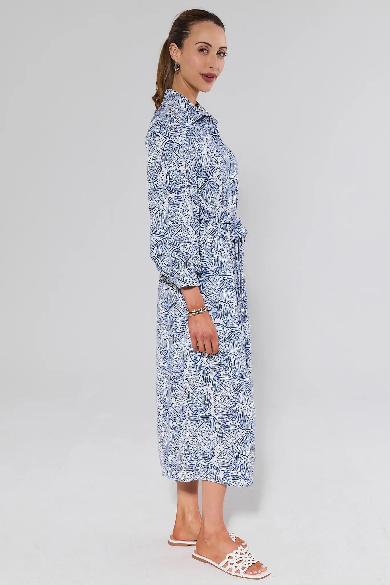 side shot Woman wearing a long blue floral dress against a white background