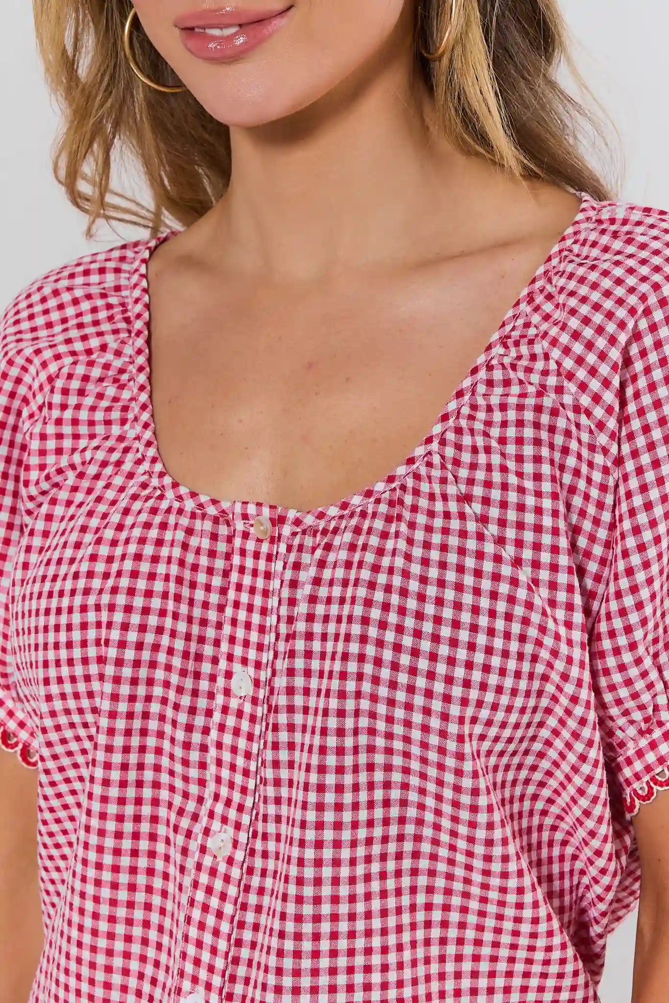 close up Red and white checkered blouse worn by a person on a plain background