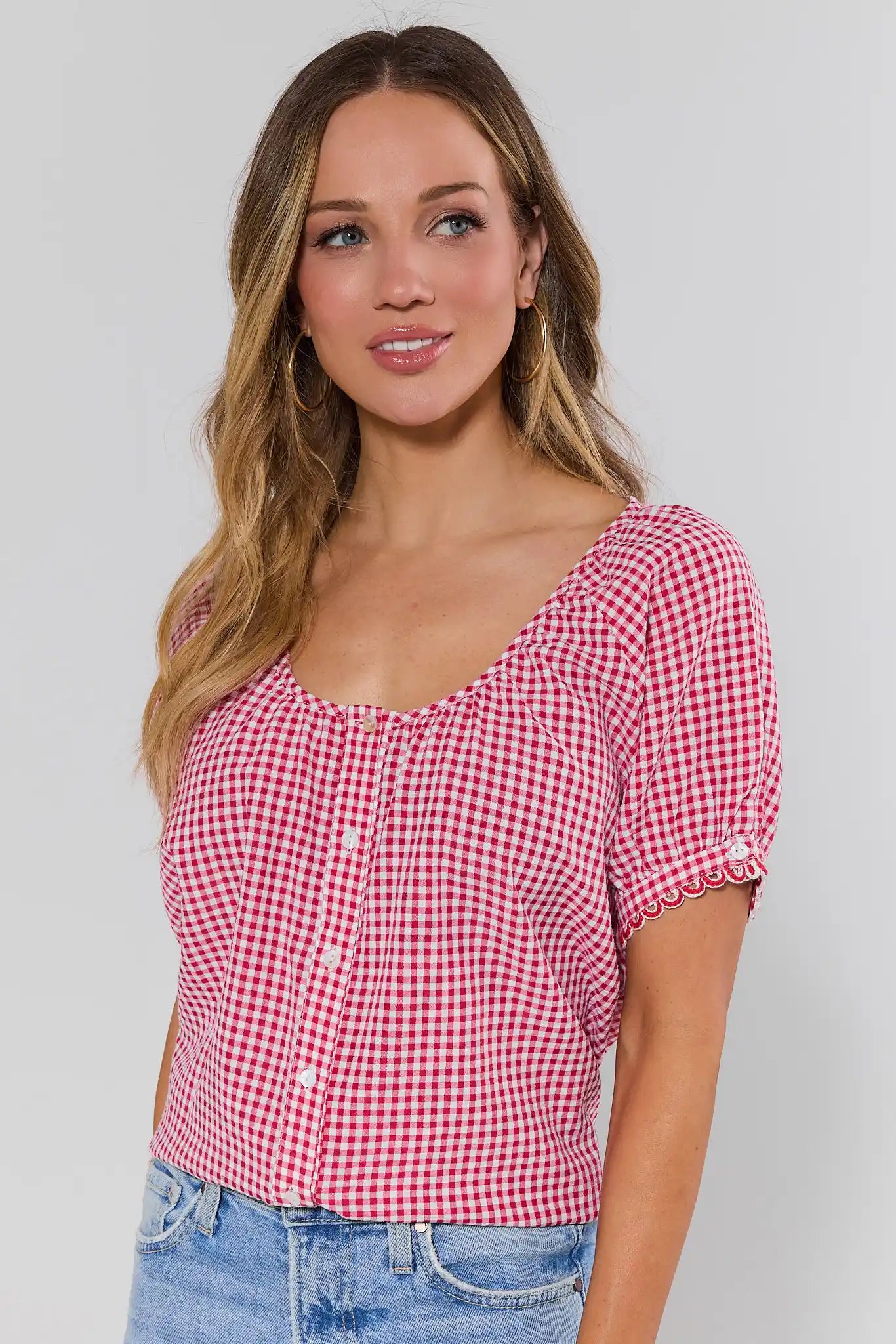 side shot Woman wearing a red and white checkered shirt with a plain background