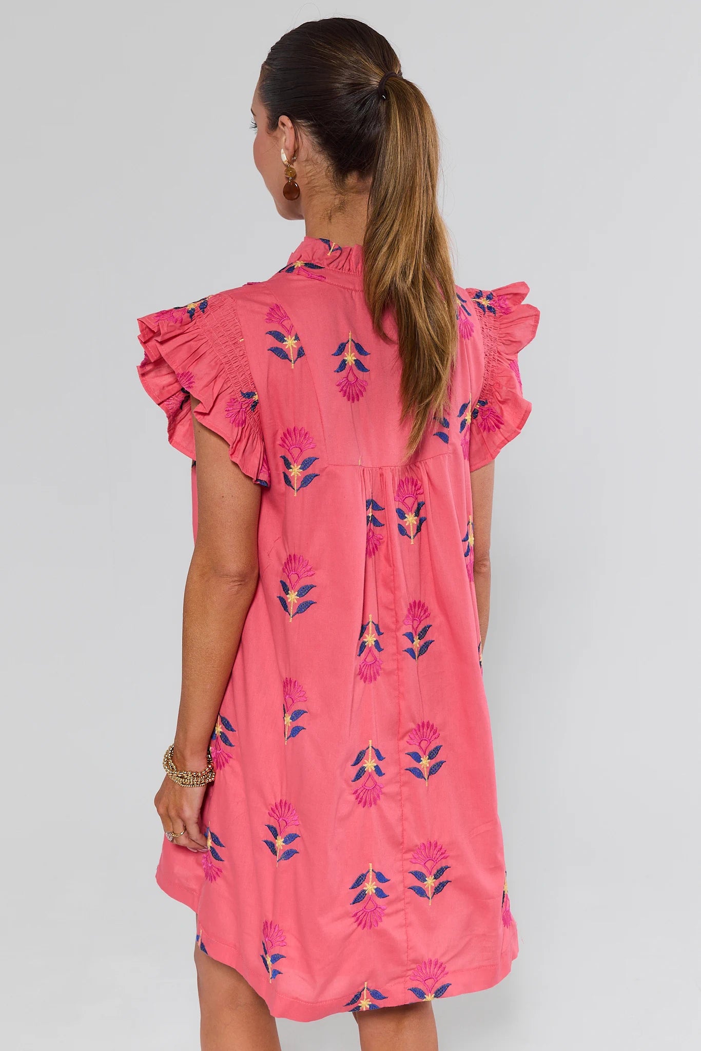 Woman wearing a pink floral dress against a gray background