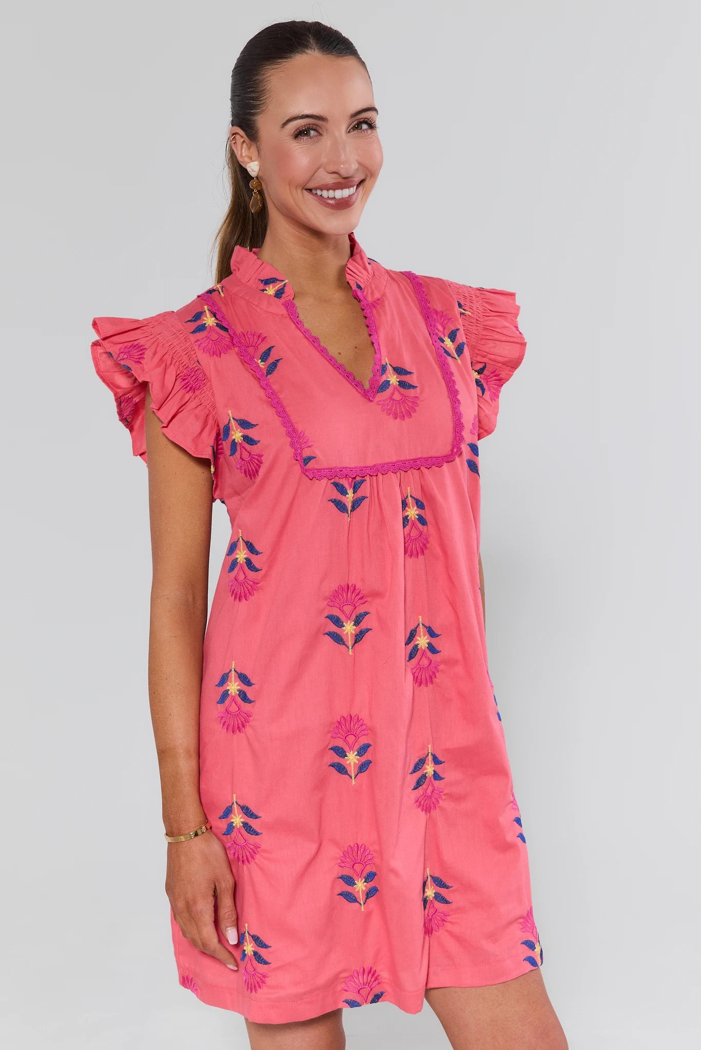 Woman wearing a pink dress with floral patterns on a plain background