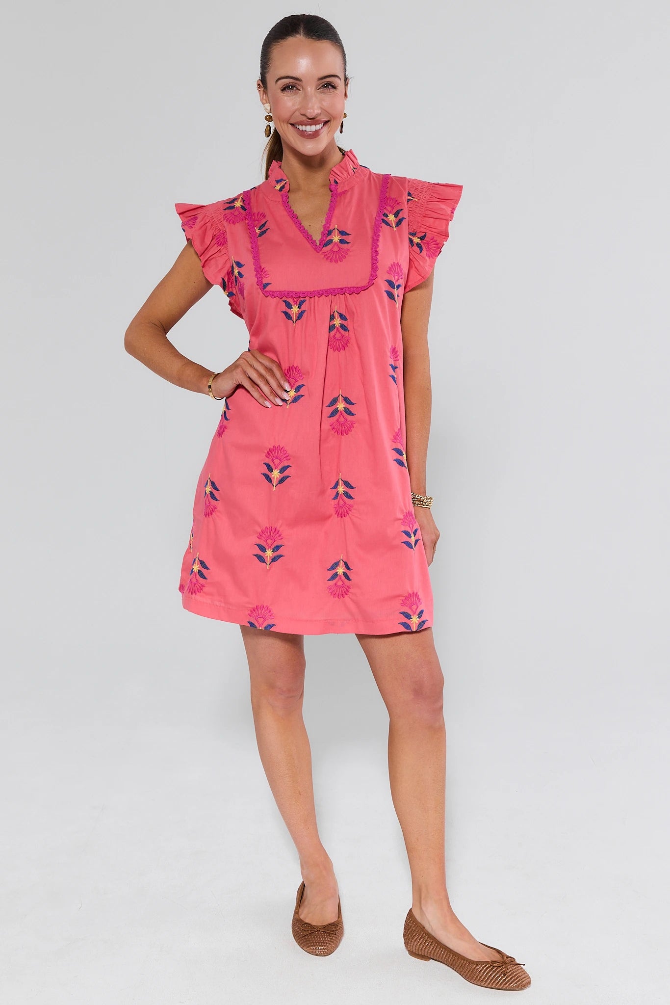 Woman wearing a pink dress with floral patterns on a white background