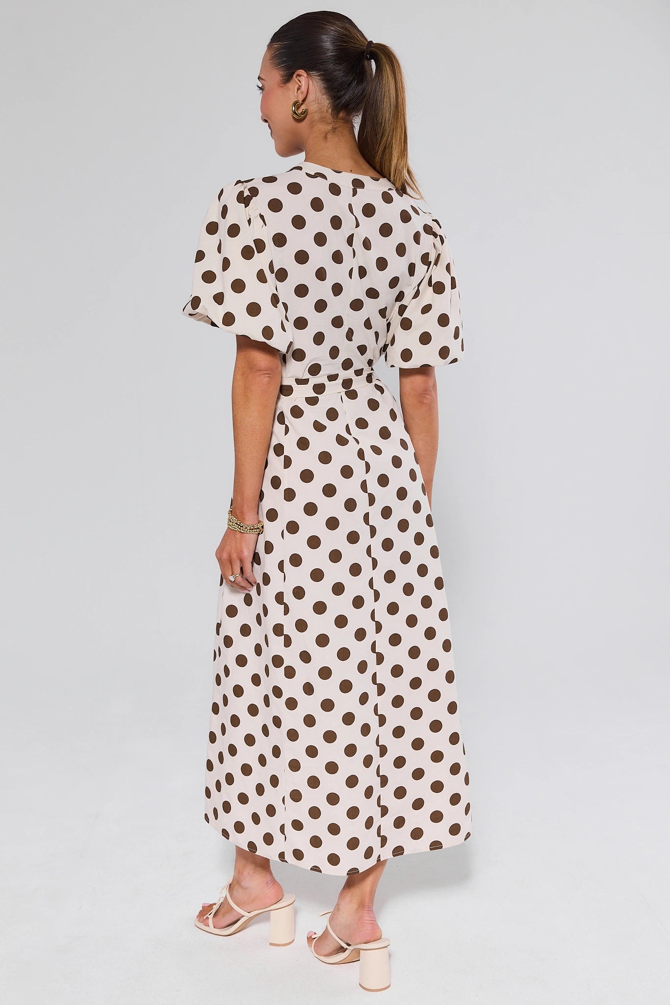 Woman wearing a polka dot dress on a plain background