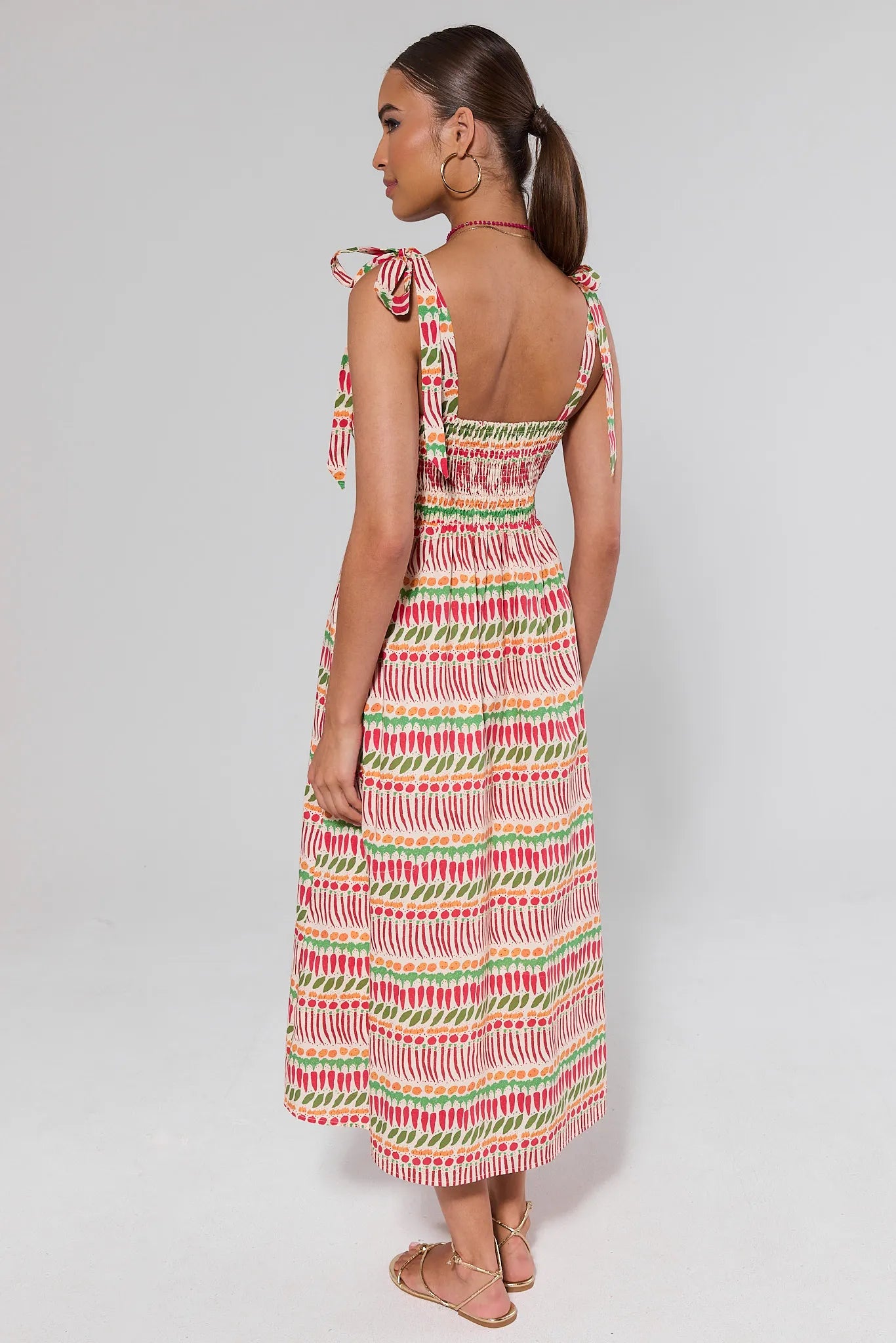 Woman standing wearing a colorful patterned dress on a white background