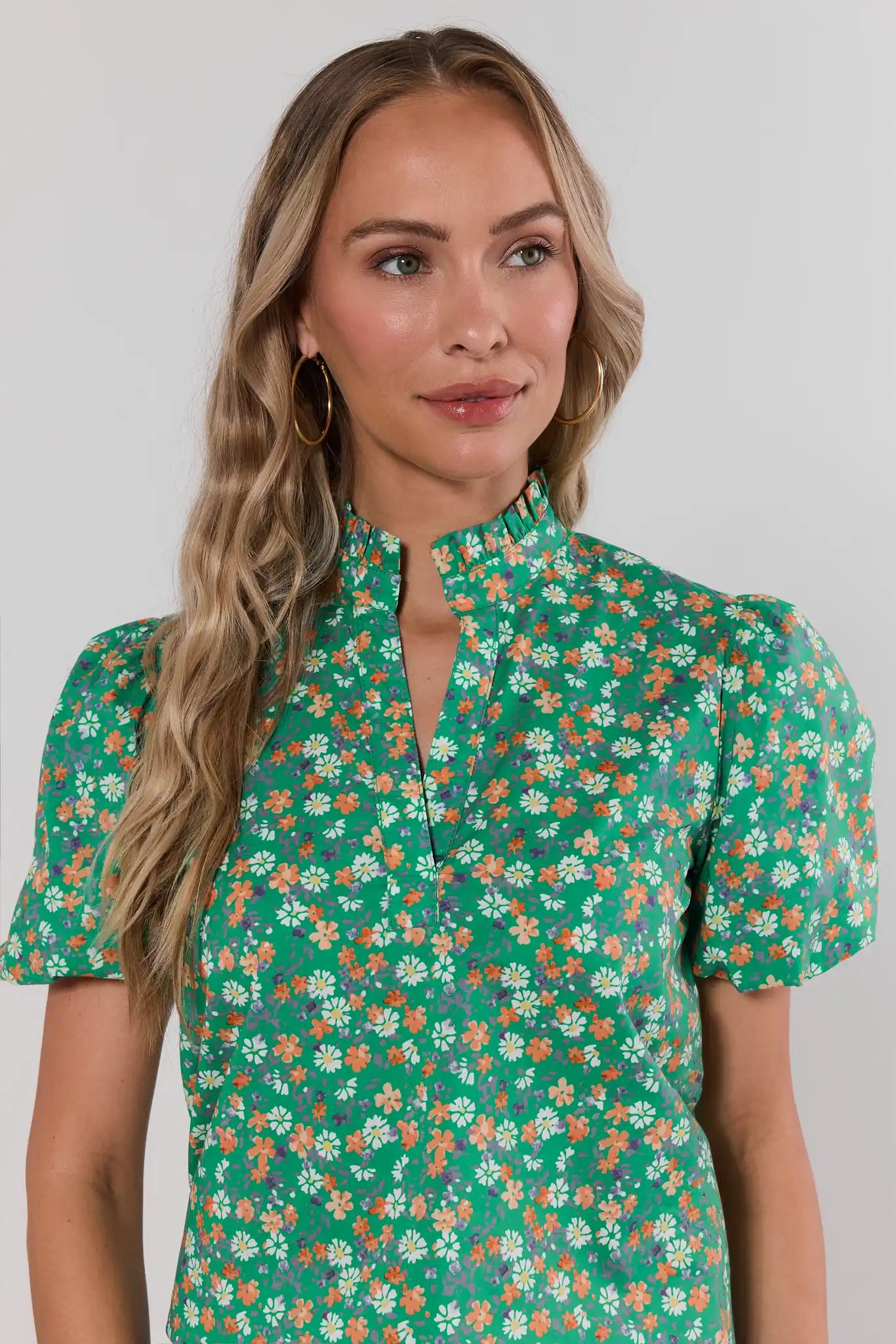 close up Woman wearing a green floral blouse against a plain background