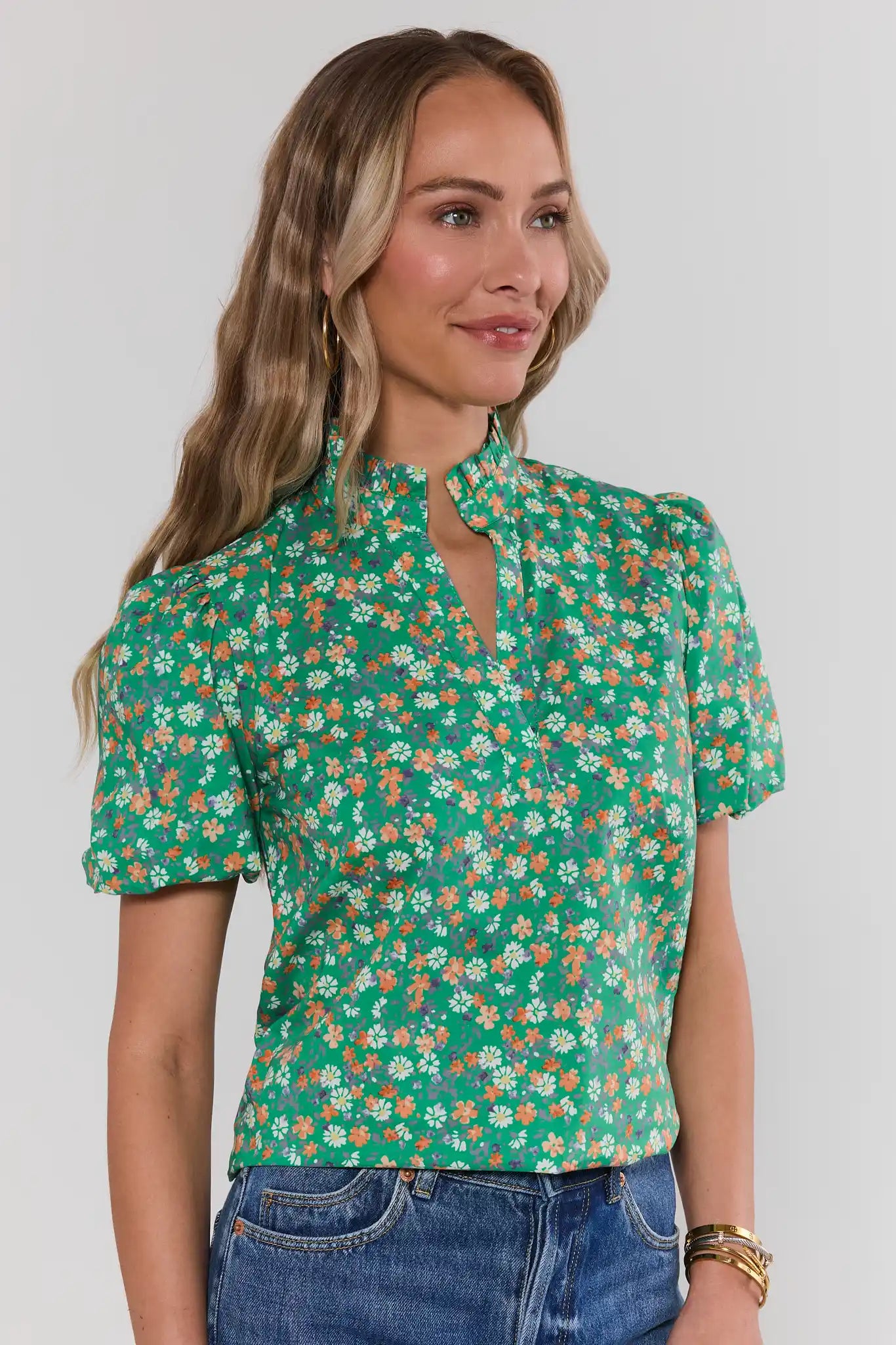 Woman wearing a green floral blouse against a white background side