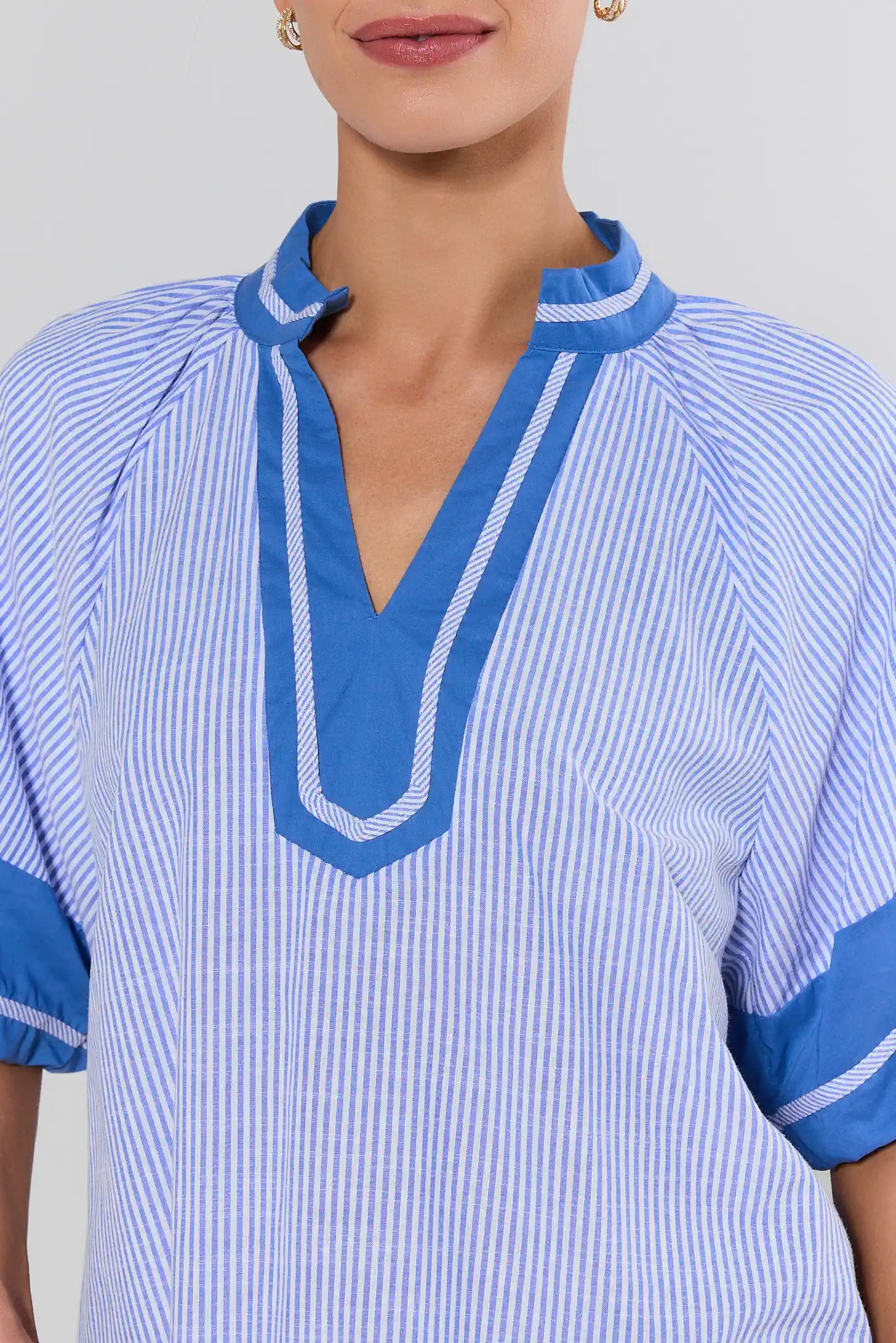 Blue and white striped shirt with a V-neckline on a plain background